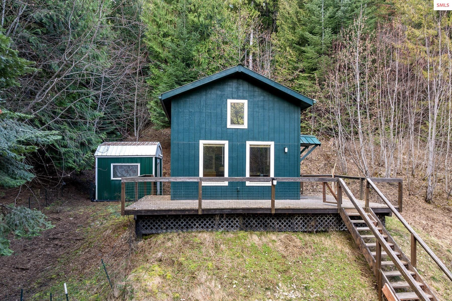 Two-story cabin, wraparound deck, storage shed.