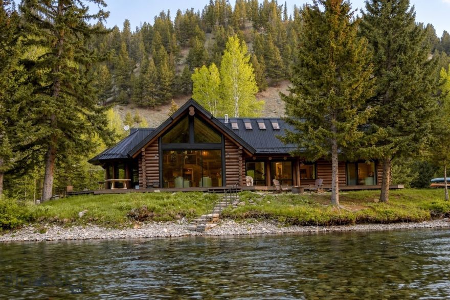 There are riverfront homes, and then there is 49622 Gallatin Road. Situated on over five acres with more than 900 feet of Blue Ribbon fishing frontage, this isn't just a mountain house—it’s a front-row seat to the best of the Gallatin River. Whether you’re watching otters play from the deck, spotting elk across the water, or casting into one of the most productive fishing holes in the canyon, this property manages to feel both deeply peaceful and incredibly convenient.
The home opens into a welcoming gallery entry flanked by storage. From here, the layout flows naturally into spaces designed for both privacy and connection. To the left, the primary suite offers a true escape. The en-suite bathroom features a freestanding soaking tub positioned to take in river views. Above the primary bedroom,  a whimsical loft adds character—perfect for a kids' hideaway or extra storage. Nearby, a versatile bonus room currently serves as a bedroom but is ready to become your gym, craft room, or gear hub. A dedicated home office sits off the main hall, offering a backdrop of the Gallatin that makes checking emails a pleasure.
The heart of the home is defined by vaulted ceilings and a modern gas fireplace. A wall of glass curtain doors erases the boundary between the interior and the expansive deck, sitting just 20 feet from the water’s edge. Smartly appointed for the chef, the kitchen features Miele appliances and a striking leathered Taj Mahal Quartz waterfall island. A designer wood-clad pantry includes a built-in water bottle filler—a small but essential detail for Montana life.
Down the hall, a second en-suite bedroom features custom tile work and a walk-in closet. Upstairs, a guest loft offers two built-in queen beds, a full bath, and a private deck for morning coffee over the river. The property includes a fully remodeled ADU above the two-car garage. With modern finishes and elevated views, it’s an ideal setup for guests or a STR rental. The garage also features additional laundry hookups.
Adding a layer of Montana history, an original electrified cabin sits on the acreage. It’s the ultimate "fishing shack" or "she-shed," serving as a perfect focal point for entertaining, . While the property feels like a resort, it’s well-positioned for daily life: 15 minutes to Big Sky, 5 minutes to schools, and 45 minutes to the Bozeman Airport. Standing on the deck, overlooking the river, this is a property that truly moves the soul.