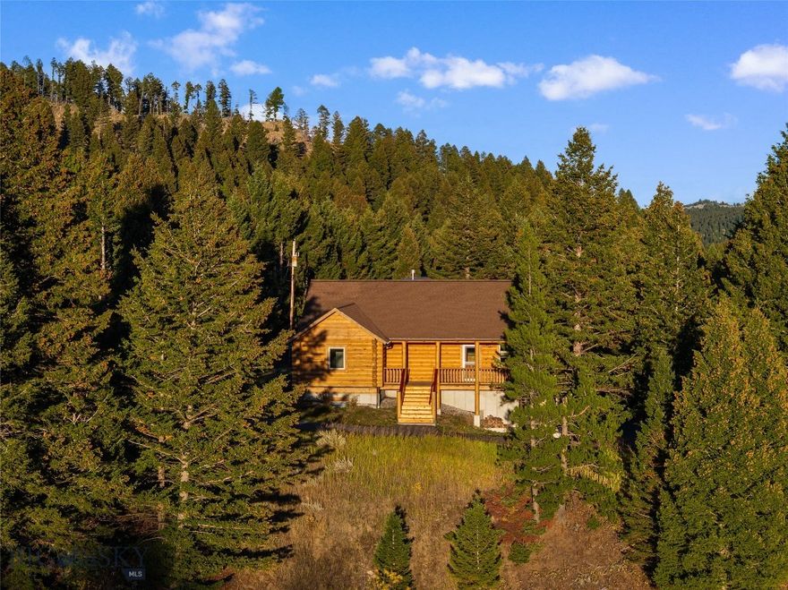 Experience an exceptional Montana lifestyle just 20 minutes from downtown Bozeman, offering both privacy and everyday convenience. This meticulously maintained custom log residence on 21.94± acres with private access to fishable Brackett Creek provides an ideal balance of space, seclusion, and accessibility. Thoughtfully refreshed with interior updates, the home features vaulted ceilings, expansive windows, hardwood floors, and open-concept living spaces that frame sweeping views of the surrounding meadows, timber, and creek.

The main level provides comfortable single-level living with two bedrooms, two baths, and a well-appointed kitchen with custom cabinetry and generous counter space. The recently finished lower level includes two additional bedrooms, a bonus/multipurpose room with built-ins, and direct access to the attached two-car garage, offering flexibility for guests, recreation, or multi-generational living. One lower-level bedroom is well-positioned and could be converted into an additional bathroom, adding future value and functionality.

Outdoor living is highlighted by a covered deck overlooking mature natural landscapes and abundant wildlife. A 32' x 30' heated and insulated shop provides ample space for vehicles, equipment, or workshop use. Ideally located near Bridger Bowl, Crosscut, and the Brackett Creek Trailhead, this property is well suited for those seeking year-round recreation, privacy, convenience, and a true Montana retreat, with excellent potential for both short- and long-term rental income.