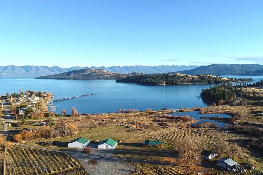 Experience one of the most versatile and visually striking properties on Flathead Lake. Set on 32.55 acres with 464 feet of premier waterfront, this estate combines privacy, scale, and functionality in a way that’s increasingly hard to find. Dayton Creek winds through the property, adding a rare natural feature that enhances both the setting and usability of the land.

The main lake residence offers 1,589 square feet with three bedrooms and two bathrooms, positioned to capture unobstructed views of Flathead Lake and Wild Horse Island. Designed for easy lake living, it features a custom rock fireplace, expansive deck, and seamless indoor outdoor flow for entertaining or quiet evenings looking over the water.

A secondary residence adds both flexibility and character. Originally built in 1908, the 916 square foot farmhouse includes one bedroom, two bonus rooms, one bathroom, and a 326 square foot finished attic. Surrounded by mature cottonwoods and a private yard, it offers a distinct setting for guests or extended stays.

The improvements on this property set it apart. A 3,132 square foot winery building includes a private saloon with lake views, a large shop and storage area with floor drains, two 1,200 gallon water storage tanks with irrigation to RV pad locations, and 200 amp electrical service. The 2,988 square foot venue building is designed for gatherings, featuring a glass overhead door, expansive windows with lake and mountain views, seating capacity for approximately 150 guests, ceiling sound panels, and an outdoor 25 by 60 foot patio with party lighting. Additional infrastructure includes a 30 by 40 shop and 33 gravel RV pads with water and electric.

Whether used as a private lakefront retreat, multi generational compound, event venue, or income producing investment, this property offers a rare combination of frontage, acreage, and built infrastructure on the LARGEST freshwater lake west of the Mississippi!