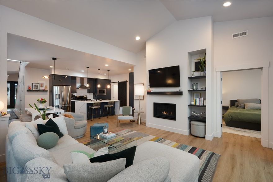 Welcome to 1327 Windrow Drive, a beautifully designed luxury townhome in the coveted Flanders Mill subdivision. This luxurious 3-bedroom, 2.5-bath townhome offers 1,911 square feet of thoughtfully designed living space, combining elevated finishes with effortless, low-maintenance living. Ideally suited for those who value convenience, flexibility, and refined design, this home allows you to enjoy everything Bozeman has to offer—without the time-consuming upkeep of a traditional single-family residence. The main level features a highly desirable primary suite with a spa-inspired ensuite bathroom and heated floors, providing comfort and functionality for everyday living. The open-concept layout showcases elevated finishes throughout, including quartz waterfall kitchen countertops, custom built-ins, a striking steel staircase, and expansive windows that fill the home with natural light. A cozy gas fireplace with mantel anchors the living space, complemented by high-end window shades and refined architectural details. Upstairs, two spacious bedrooms, a full bathroom, and a lofted living area offer flexibility for a second lounge, media space, or home office, along with a conveniently located laundry room. An attached two-car garage adds everyday practicality and ample storage. Located in Flanders Mill, this home offers access to community parks, trails, and ponds, with easy proximity to downtown Bozeman, shopping, dining, and outdoor recreation. Whether used as a full-time residence or a lock-and-leave option, this low-maintenance luxury townhome delivers a refined Montana lifestyle.