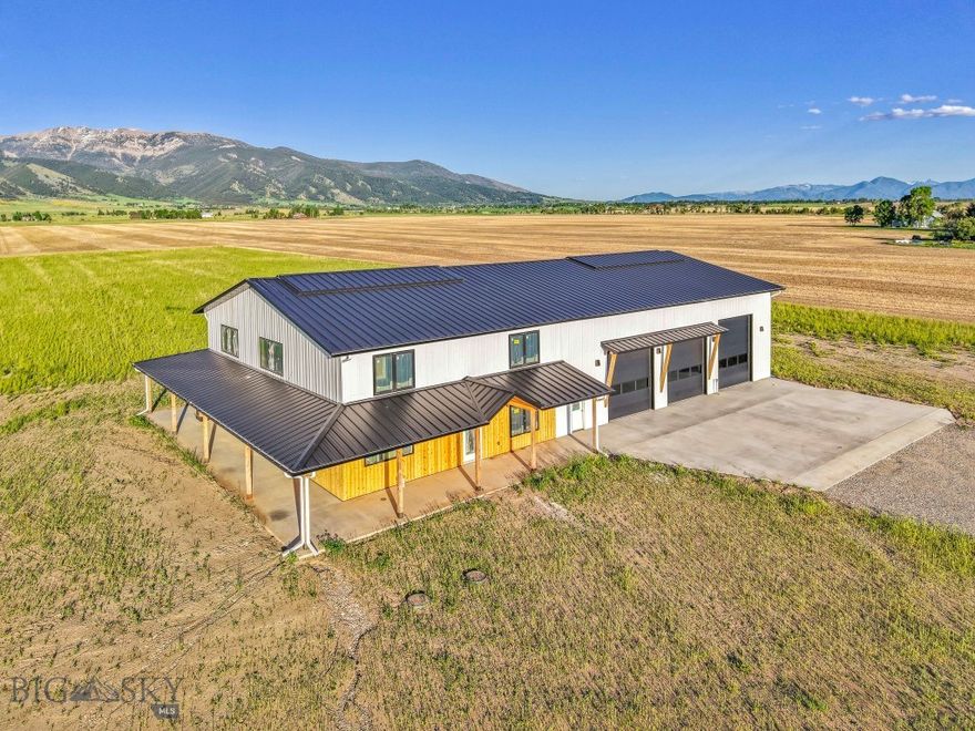 This property is the ultimate combination of modern elegance and expansive functionality with incredible front row views of the Bridger Mountains. This stunning barndominium-style home is a unique property that is ideal for enthusiasts of outdoor recreation, automotive collectors, professionals in construction-related fields or just someone looking for extensive space for both living and working. Central to this magnificent home is a massive 3-bay shop/garage attached directly to the residence, complemented by an additional 40x60 shop and a 30x40 pole barn. The garage is equipped with high bay doors (two 12x12 and one 14x12) and a convenient drive-through door leading to another patio, perfect for admiring the breathtaking scenery. The garage also features RV hookups, including 240 power and an indoor dump spot, as well as several floor drains, making it ideal for storing and maintaining large vehicles and equipment. Step inside to find a grand living room with high ceilings and strategically placed windows that ensure the mountain vistas are gloriously framed in every view. The kitchen is a masterpiece of design, boasting a 12-foot island with a sink, built to accommodate a 60-inch refrigerator and an oversized range, with both traditional cabinetry and floating shelves for a modern touch. The main level master suite offers private patio access for quiet mountain gazing, a large en suite bathroom, and a walk-in closet connected directly to the laundry and mudroom for ultimate convenience. The upper level features a loft space perfect for an office or extra family room, overlooking the open living and dining areas, with two additional large bedrooms and a full bathroom. Crafted with metal siding and roofing and featuring details of fir siding, this home is built to last and designed with energy efficiency in mind, including central air conditioning and adjustable LED lighting throughout. This property is not just a home; it's a lifestyle solution for those who value space, quality, and a spectacular setting to enjoy their hobbies and passions. Whether you're tinkering with your car collection, storing seasonal gear, or managing work equipment, this home delivers the perfect blend of practicality and pleasure.