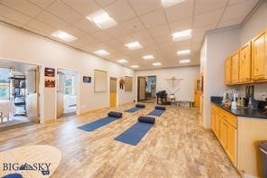 This listing offers a unique opportunity to acquire office suites where all Tenants are health and wellness & synergistic in nature.  The wellness center/office space spans 3,311 square feet and features 11 treatment rooms along with a spacious studio designed for a variety of wellness classes.  There is additional expansion space available for purchase with 1,400+ SQFT (7 office suites) for a total of 4,732 SQFT if purchased all together.

Unit F serves as the main waiting area and is characterized by its bright and open layout. It includes a front desk, an attached kitchenette, six treatment rooms, and additional storage space and double doors that lead to a covered deck with south-facing mountain views.

Adjacent to this unit is suite G, which contains a large studio utilized for formal and informational educational classes, wellness practices, and classes hosted by practitioners. This unit also comprises five treatment rooms, has a storage closet, a sink with a granite countertop, and cabinets. There are high double doors that lead to a covered deck with stunning Northeastern Bridger Mountain views.  

Across the hallway, Unit E is home to seven treatment rooms primarily used by wellness practitioners & could be purchased in addition. Each treatment room is thoughtfully designed to accommodate massage tables while ensuring ample space for movement.

The homeowners’ association (HOA) is in good standing and has successfully completed significant exterior upgrades. Additional amenities of the property include an elevator providing access to the second floor, shared bathrooms in common areas, and individual air conditioning units for each unit. Furthermore, the property boasts extensive common area parking with over 20 on-site spaces along with ample off-street parking.  

This real estate offering represents a remarkable chance to expand a wellness business- but it does not to remain as such. While there is potential to maintain the current vision, there are also opportunities for the new owner to implement their own ideas for growth. Most leases are not long-term, allowing for flexibility in providing notice when necessary; however, existing tenants are valued and many would prefer to continue their leases.