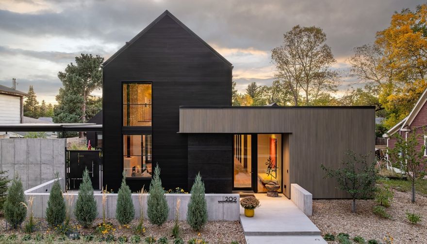 Discover The Urban Sanctuary—a refined, modern retreat where architectural craftsmanship, natural materials, and thoughtful design come together in quiet harmony. Tucked into Bozeman’s historic southside, this custom residence offers rare privacy and serenity while remaining just moments from downtown and Montana State University. Step inside to a warm, elevated interior anchored by a dramatic vaulted great room with floor-to-ceiling doors that open fully to the courtyard for seamless indoor–outdoor living. Natural light fills the space, highlighting wide-plank white oak flooring, custom oak cabinetry, a gallery-style art wall, and a sculptural fireplace. A chef’s kitchen features a Bluestar 8-burner professional range, Thermador panel-ready refrigerator, quartz waterfall island, terrazzo backsplash, and extensive built-in storage—perfect for cooking, gathering, and entertaining. A lofted lounge above creates a second relaxed living space for movie nights or quiet reading. The main-level primary suite is a peaceful sanctuary, opening directly to a secluded wellness courtyard and a custom Finnleo sauna. The spa-inspired bath includes a composite soaking tub, ½" glass shower with dual waterfall heads, and ambient lighting. Upstairs are two additional bedrooms and a beautifully appointed full bath, offering comfort for guests or family. A main-level powder room adds convenience. A detached one-bedroom casita (ADU) mirrors the same modern aesthetic and craftsmanship, providing its own kitchen, living area, full bath, and private outdoor retreat. Ideal for personal or short term rental guests, a caretaker, multi generational living or a dedicated studio/office. Designed for stillness and connection, the property features two distinct courtyards with artisan steelwork, raised garden beds, lush landscaping, and intimate gathering spaces. Enjoy a covered outdoor lounge with a Malm wood fireplace, a zen garden framed by custom steel trellises, and sculptural basalt art. Professionally designed and installed landscaping includes full irrigation, lighting, and fruit/shrub trees. A sound-insulated Art/Music/Fitness Studio with natural light provides flexible creative or wellness space. The finished, insulated two-car garage includes an extra-tall bay suitable for an RV and is equipped with a Hot Dawg heater. A truly rare offering in the heart of Bozeman, The Urban Sanctuary balances privacy, artistry, and modern luxury in one cohesive, inspired property.