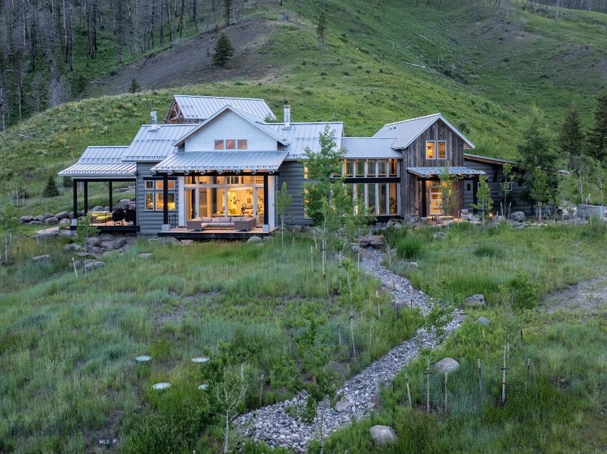 A rare offering in Bridger Canyon, Alpen Haus is a breathtaking 225-acre estate on three parcels that captures the essence of Montana’s beauty, privacy, and refined living. Thoughtfully designed by Faure Halvorsen Architects and built by Battle Ridge Construction in 2017, this 5,396 sq. ft. residence offers timeless architectural integrity, modern comforts, and a seamless blend of form and function. The home features 4 bedrooms, 3.5 bathrooms, and a versatile floor plan spread across three levels. Vaulted ceilings and expansive windows in the great room frame dramatic views of the Bridger Mountains, while a wood-burning fireplace with gas assist adds warmth and ambiance. The open-concept layout connects the great room to the dining area and chef’s kitchen—outfitted with premium appliances, custom cabinetry, and sleek stone surfaces—making it ideal for entertaining or everyday living. Outside, the home is surrounded by newly designed landscaping, tranquil water features, and two elevated decks that invite you to enjoy sweeping vistas in every season. A two-track road leads to the National Forest boundary, offering direct access to hiking, horseback riding, and backcountry exploration. Whether you're hosting guests or seeking solitude, the outdoor experience is immersive, peaceful, and uniquely Montana. Additional highlights include a stylish Airstream guest house—perfect for friends or extended stays—along with a large secure vault room, offering both charm and practicality. Set across three parcels, this estate delivers an extraordinary sense of privacy and possibility. The land itself is a tapestry of meadows, trees, and mountain views, creating a near-private park feel that is both wild and refined. Just minutes from downtown Bozeman yet a world apart, Alpen Haus is a sanctuary where nature, design, and luxury converge.
