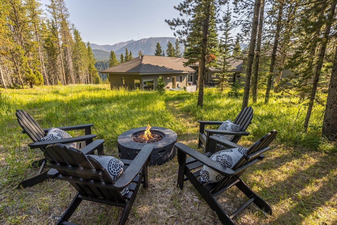 Nestled on a peaceful cul-de-sac, this 4-bed, 3.5-bath mountain retreat offers privacy, comfort & natural beauty. Set on a .75 acre lot, the home backs to a 20-acre Spanish Peaks Lot, providing privacy, tranquility & expansive views. Spanning 4,235 sf across three levels, the 3,098 sf MAIN LEVEL features an open-concept kitchen-living-dining room, half bathroom, master suite w/ walk-in closet & en-suite bath, 2 additional bedrooms, full bathroom, mudroom, laundry room, front porch, back patio w/ hot tub, & covered porch. The 743 sf UPPER LEVEL includes a full bathroom, bedroom, family room, built-in desk & kitchenette, offering privacy from the main living area, ideal for a kids zone, guests, renters, or a mother-in-law suite. The 394 sf LOWER LEVEL includes a sauna, fitness room, storage & mechanical room with access to crawl space. The oversized 750 sf two-car garage has room for large vehicles, storage & potential workshop. Expansive windows bring in abundant natural light, offering views of the surrounding mountains & pine trees. The master suite & main living area offer access to the hot tub. A highly efficient Danish-designed Scan wood-burning stove provides heat & ambiance, complemented by radiant in-floor heat powered by a new boiler installed in 2023. And a whole-house fire suppression system adds extra safety. In 2023, the home’s interior & exterior were freshly painted & the driveway was sealed. Wildfire mitigation measures included tree removal & a gravel perimeter around the home. The surrounding landscape includes natural grasses, wildflowers, wild strawberries & trees, while a large flower bed in front blooms almost year-round. The home is wired for a generator & includes a heat tape system to prevent ice damming on the roof. Local wildlife, including elk, deer, fox & moose, frequently visit, enhancing the charm of the area. Ideally located just 2 miles from Big Sky’s Town Center, 4 miles from Spanish Peaks & Montage Hotel, 7 miles from Big Sky Resort & 9 miles from Moonlight Basin, this home offers easy access to both seclusion & Big Sky’s amenities. This property offers the perfect blend of privacy, functionality & views of nature. Whether enjoying the peaceful neighborhood, exploring nearby wilderness, or taking advantage of outdoor adventures, this home provides a one-of-a-kind living experience in Big Sky, Montana’s mountain paradise. Offered fully furnished, turn-key with some exclusions – an opportunity not to be missed! Agent owned.