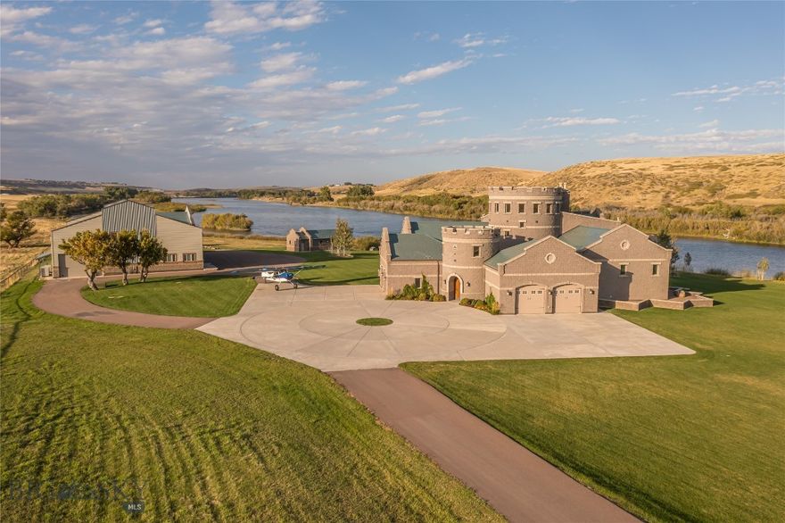 Welcome to your own majestic retreat on the banks of the mighty Missouri River! This extraordinary estate offers unparalleled privacy, surrounded by the breathtaking natural beauty of Montana's landscapes. As you approach, you'll be greeted by over a mile of pristine river frontage, providing endless opportunities for fishing, boating, and relaxation along the Missouri. The centerpiece of this remarkable estate is a stunning castle-inspired residence, exuding timeless elegance and architectural grandeur. Features such as a cedar-lined sauna, expansive wine cellar, turret with reading room, two attached garages, multiple fireplaces, and the bold, castle-like courtyard complete with gargoyles, add to the allure of the property. The home is thoughtfully laid out with wings for the homeowners and guests. The main wing includes a bedroom, walk-in closet, ensuite bath, office, laundry room, and one of the attached two-car garages with direct entry. In the guest wing, you’ll find three guest bedrooms, two baths, a 2-car garage, ample storage, and a guest laundry room. The main living area contains a grand entry with vaulted ceiling and an open concept kitchen, living room, and dining room. The exquisite views over the expansive, plush lawn to the river and scenic open lands will take your breath away. Cozy up to the living room fireplace and enjoy the abundance of wild animals and bird life in your backyard. The round dining room has spectacular views in every direction and is highlighted by a custom-made round table to complement the space. Aviation enthusiasts will be delighted by the inclusion of an airplane hangar providing convenient access for travel and exploration. The possibilities are endless for those with a passion for flight and adventure, whether urban or backcountry. For the avid boater or water enthusiast, a remarkable boathouse awaits, complete with a concrete ramp for effortless access to the river. Imagine embarking on leisurely cruises or exciting adventures right from your own backyard. For those seeking space for hobbies or projects, a large workshop within the hangar offers ample room for creativity and craftsmanship, while the two-bedroom guest quarters with a full kitchen provide comfortable accommodations for visitors or extended stays. This exceptional property offers a rare opportunity to own a piece of Montana's pristine wilderness, where every day brings new adventures and cherished memories.