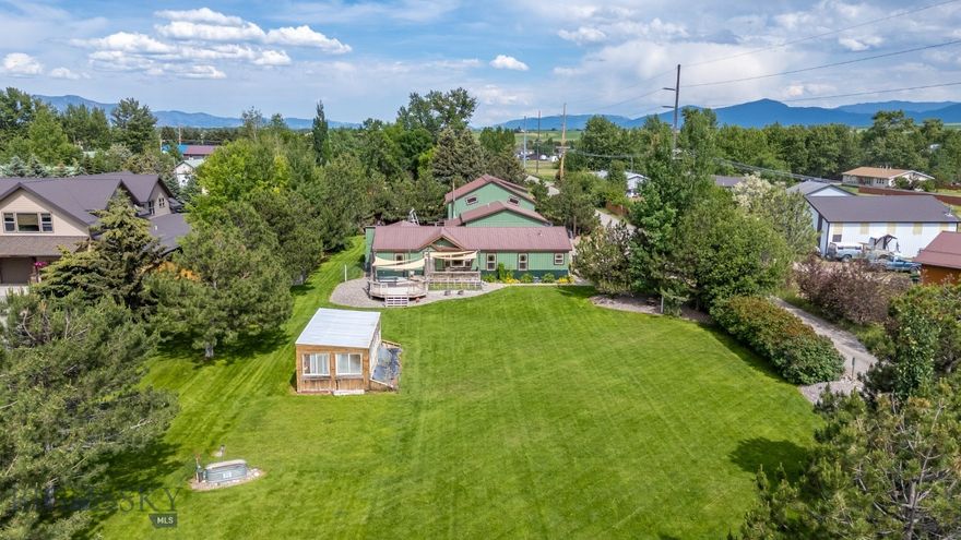 Charming Home with Expansive Shop located in Four Corners area. Situated on just under an acre, this unique property offers the perfect blend of privacy, practicality, and convenience—with no HOA and minimal covenants that offers flexibility without sacrificing community standards. The property features a cozy single-level home, a 2,348+ sq ft shop/garage with separate power and heat, and a beautifully landscaped outdoor oasis perfect for both relaxing or entertaining. Step inside from the back porch into a spacious mudroom—an ideal transition space offering room for freezers, gear storage, or a catch-all space. From here, you'll find a well-appointed laundry area to the right and a thoughtfully designed kitchen to the left, offering abundant cabinetry and a seamless connection to the large dining area. The circular layout continues into the welcoming living room, where vaulted ceilings and a picture window invite natural light and views of the lush front yard and expansive deck. Just off the living room is the primary suite, complete with an ensuite bath featuring a walk-in Travertine-tiled shower. Three additional bedrooms and a full guest bath offer plenty of space for family or guests. Outdoors, the front yard is a true retreat—showcasing a custom-built deck with a fire pit, greenhouse, mature privacy trees, and a flourishing garden with strawberries, rhubarb, cucumbers, and more. Whether you’re hosting friends or enjoying a quiet evening, this space is designed for year-round enjoyment. The east side of the home features an oversized two-car garage and the impressive 2,348 sq ft shop, separately metered with three phase power and ready for work or play. With its own bathroom, wood boiler for winter warmth, built-in storage, and an upper mezzanine level, the shop is ideal for entrepreneurs, collectors, or those in need of substantial workspace. This rare property offers comfort, flexibility, and functionality—all just moments from local hot springs, dining, and entertainment. A true gem in the heart of the Gallatin Valley.