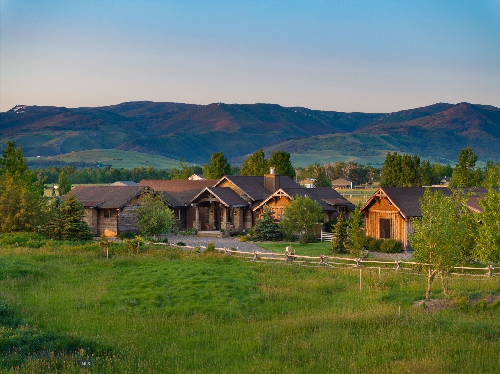 Welcome to your dream Montana estate—20 acres of refined Western living with sweeping 360 degree views of the Gallatin, Spanish Peaks, and Bridger mountain ranges. Located just two minutes from world-class fly fishing on the Gallatin River and surrounded by endless recreation, this custom-built estate is the ideal primary residence, vacation retreat, or equestrian sanctuary. Thoughtfully designed for comfort and ease, the single-level main home spans 2,703 square feet, and blends rustic elegance with modern function. Artisan trusses, handcrafted entry details, and premium finishes throughout reflect the home’s quality craftsmanship at every corner. The main home features elegant circle-sawn white oak flooring, marble and granite countertops, and thoughtful luxury touches throughout, as well as a spacious 800 square foot attached garage. The open-concept layout connects indoor spaces effortlessly, while expansive windows frame breathtaking mountain vistas from nearly every room. Step onto the back patio and enter a true backyard oasis, complete with expansive irrigated lawn, multiple garden areas, a custom fire pit feature, horse shoe pit, and some of the most commanding mountain views in the area. A separate 1,033 square foot guest/bunkhouse offers private accommodations for visiting guests and family members, or can be used to generate impressive rental income. Complete with it's own full kitchen, bathroom, and laundry room, the bunkhouse is ideally positioned for both privacy and access. Perfectly suited for horse lovers, this property features two horse sheds, dry lot corrals, a 200’ x 240’ riding arena, and fully fenced pastures. The front field produces timothy and brome hay annually, and the property includes valuable water rights to the Noble Ditch, which flows along the eastern edge of the property. Additional outdoor amenities include an invisible fence system for dogs, and endless opportunities for riding, hiking, and exploring the surrounding countryside. The property enjoys the added flexibility to be subdivided one time, adding limitless potential. Located just minutes from the Gallatin Gateway School, local dining and music venues, and additional public river access points, this estate combines the privacy of country living with the convenience of a prime location. Whether you're seeking tranquility, adventure, or income potential, this extraordinary Montana property delivers it all.