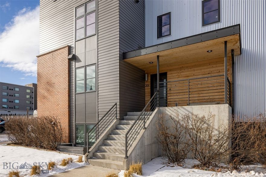 An exceptional expression of luxury in the heart of downtown Bozeman, this highly sought-after Block M custom townhome offers refined urban living at its finest. Impeccably designed and richly upgraded, this coveted corner-unit residence features a light-filled open floor plan with sophisticated finishes and effortless flow for both everyday living and elevated entertaining. The home is thoughtfully crafted for both versatility and comfort. A private in-home elevator provides seamless access across all levels, adding convenience and appeal. The home captures unobstructed, sweeping views of the valley and surrounding mountains, dramatically showcased from two expansive rooftop patios, one complete with a private hot tub for year-round relaxation under Montana’s big sky. Just steps from Bozeman’s premier dining, boutiques, and art galleries, this residence delivers an unrivaled walkable lifestyle. With its own exterior entrance for complete privacy, the one-bedroom basement apartment offers exceptional flexibility, perfect for rental income, hosting guests, or creating a secluded home office. Complete with an oversized heated two-car attached garage with EV charging capability, this rare offering blends architectural elegance, adaptability, and location into one truly remarkable downtown retreat.