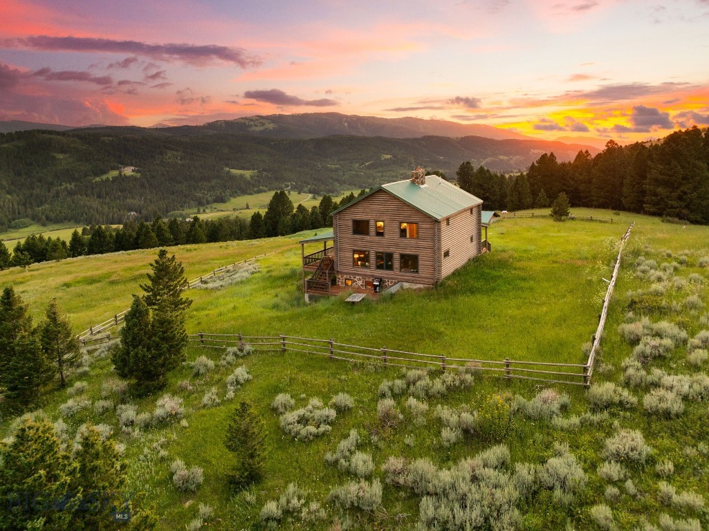 Tucked into the scenic hills off Trail Creek, this beautifully reimagined log home offers the ultimate in luxury mountain living on 27 private acres with panoramic views. Thoughtfully updated with high-end craftsmanship and modern conveniences, this mountain retreat combines rustic charm with refined details, all just 25 minutes from downtown Bozeman or the charming town of Livingston. Inside, expansive windows—custom-built by Montana Sash and Door—flood the open-concept main floor with natural light and showcase sweeping mountain views from every angle. The kitchen, dining, and living areas flow seamlessly together, centered around a striking stone fireplace with a handcrafted fireback by Montana Ironworks. Upstairs, the spacious primary suite features its own fireplace, en suite bathroom, and unmatched views. Two inviting guest rooms bedrooms and another full bathroom blend comfort with vintage character, and offer ample space for family and guests. The walkout basement offers flexible living space, including a family room, a guest bedroom, updated mudroom, and full bathroom. This home has seen extensive upgrades, including a full exterior restoration with fresh chinking, staining, and custom copper log end caps, as well as new exterior doors and a fully refinished wraparound deck. Practical enhancements include a backup generator, a secondary well with pump, and a 1,000-gallon in-ground propane tank—all contributing to the home’s self-sufficiency and comfort. Surrounded by timber and open meadows with cleared space for agricultural use, this property offers peace, privacy, and unspoiled natural beauty. With a detached two-car garage and location in the LaMotte School District, this mountain retreat is a rare blend of classic Montana aesthetics and modern luxury, providing an ideal year-round residence or vacation retreat.