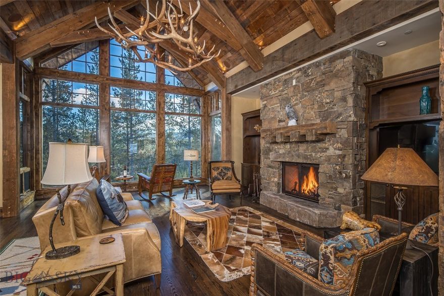 The BEST of both worlds with close proximity to both Yellowstone Club's private entrance, Spanish Peaks Mtn Club, Big Sky Town Center and a quick walk to fly fishing on the Westfork of the Southfork of the Gallatin River.  Timeless timber-frame and stone home on 2.18 beautifully wooded acres. This stunning home blends rustic charm with mountain elegance and low maintenance with a new DaVinci roof and freshly painted interior. With a total of 5 bedrooms all en suite + 2 powder rooms + 3 car garage ensuring privacy and space for all guests. Main Level: Walk in the custom front door and you immediately feel like you're in a snow globe with floor to ceiling windows allowing the morning sun to stream in or the warm glow of the alpenglow sunsets, spacious open living, dining and kitchen with a floor to ceiling stone and timber wood burning fireplace. Easy living with a spacious primary suite, featuring a luxurious en-suite bathroom + outdoor shower and a walk-in closet. Adjacent to the primary suite is an executive office, perfect for a remote office when privacy is needed or overflow guest sleeping quarters. The chef's kitchen is open to the living and dining area to ensure you don't miss a conversation or football score while cooking with a separate wet bar to ensure ideal entertaining. The dining area seamlessly flows from the kitchen and living room, creating an inviting atmosphere. Step out onto the expansive deck, complete with an outdoor wood-burning fireplace—perfect for enjoying cooler evenings or gathering with friends and family. Large mudroom (a must in the mountains!) and large laundry room. Lower Level: A large family room provides ample space for the pool table with a comfortable gathering space for watching football. A large wet bar, glassed-in wine cellar with a Colt 45 as the door handle, separate workout room & walkout to an outdoor hot tub. Also includes 2 bedrooms both en suite + laundry room. Upper Level: Above the large 3-car garage, you’ll find an additional private living room and 2 additional en suite bedrooms. Offered fully furnished. Golf or Ski/Social membership is available upon application and club approval, with membership deposit due by closing—adding another layer of amenities to this exceptional property.