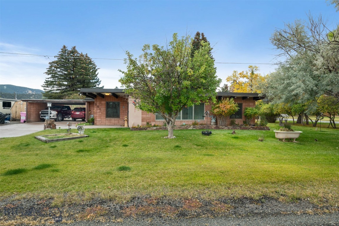 Welcome home to this charming single-level custom residence!
With 4 bedrooms and 2 bathrooms, the thoughtful floor plan offers both spaciousness and comfort. As you step through the front door, you’ll be greeted by a stunning floor-to-ceiling wall of windows and a grand rock fireplace, creating a warm and inviting centerpiece for the living area. The home features both a formal dining room and a sunny breakfast nook, giving you plenty of options for entertaining and everyday living. Two bedrooms and one bathroom are located on each end of the home, providing flexibility for bedrooms, guest quarters, or office space. The utility room includes a laundry area with a wet sink, perfect for handling messy projects and keeping the main living spaces tidy. Outside, the corner lot is beautifully landscaped with mature trees that provide shade and privacy—an ideal setting for outdoor gatherings. A fenced area off the back of the home offers a dedicated space for pets. For those with toys, tools, or trailers, this property truly shines. With generous parking options, a covered carport/breezeway, and a storage shed, there’s room for campers, side-by-sides, and extra vehicles—plenty of space for it all! Call your preferred real estate professional today for your private showing.