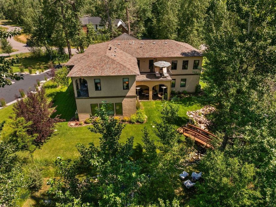 This custom-built, luxury Montana retreat blends timeless design with modern comfort, nestled on a serene, tree-lined lot that backs to community open space for added privacy and serenity. The estate has been completely refreshed with new interior paint, wool carpeting, RH/designer lighting and landscaping. Mediterranean-inspired architecture meets exceptional craftsmanship, with pride of ownership evident in every detail—from the hand-carved wood flooring and intricate ceiling accents to the artisan tile work and thoughtfully designed living spaces. The spacious chef’s kitchen is a true centerpiece, featuring rich custom cabinetry, double ovens, dual dishwashers, a walk-in pantry, and a full wet bar complete with a beverage fridge. The commanding primary suite offers a private patio, a generous walk-in closet with custom built-ins, and a spa-like en-suite bathroom with a step-up soaking tub, double vanities, and a beautifully tiled shower. Three additional bedrooms, each with their own en-suite bathrooms, ensure comfort and privacy for family and guests. A bonus room with a wet bar, a dedicated home office, formal dining room, and an upper-level laundry room with dual washer/dryer setups complete the interior. Step outside to your own private sanctuary, where a manicured lawn, two tranquil ponds with stunning koi fish, and a custom wood-burning sauna await—framed by mature trees and visited often by deer, wild turkeys, and local birds. This property offers peaceful seclusion and added acreage as it backs community open space. Enjoy convenient access to Downtown Bozeman, Big Sky, and the Bozeman Yellowstone International Airport. A truly rare opportunity to enjoy refined mountain living at its best.