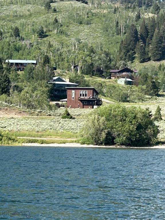Great opportunity to own a former architect's personal retreat next to Hebgen Lake with trees, terrific views and National Forest land on 2 sides. End of the road location with a protected view of the mountain peaks and Hebgen Lake from both the upper and lower levels. Basically 2 master suites, the lower with additional bunks, laundry and a high efficiency propane fireplace. The upper level has a master suite with a cozy living area, office mezzanine, wrap around kitchen with stone tile counter tops, cherry cabinets, newer upgraded appliances and a convenient breakfast bar also with stone tile. This home has a great feel with tall ceiling and tall windows to match. The 1812 sq ft home is complimented with a 2nd high-efficiency fireplace, built in ceiling speakers and CAT 5 wiring throughout. All the floors are wood plank or tile, and the home is heated with a high-efficiency propane force air furnace. Added to that you get a heated 2 car garage, a standalone heated office/workshop, making this a great home for any season. Come see the magnificent views and the perfect location of this special property. Call us today to arrange your own private showing, before it's too late.