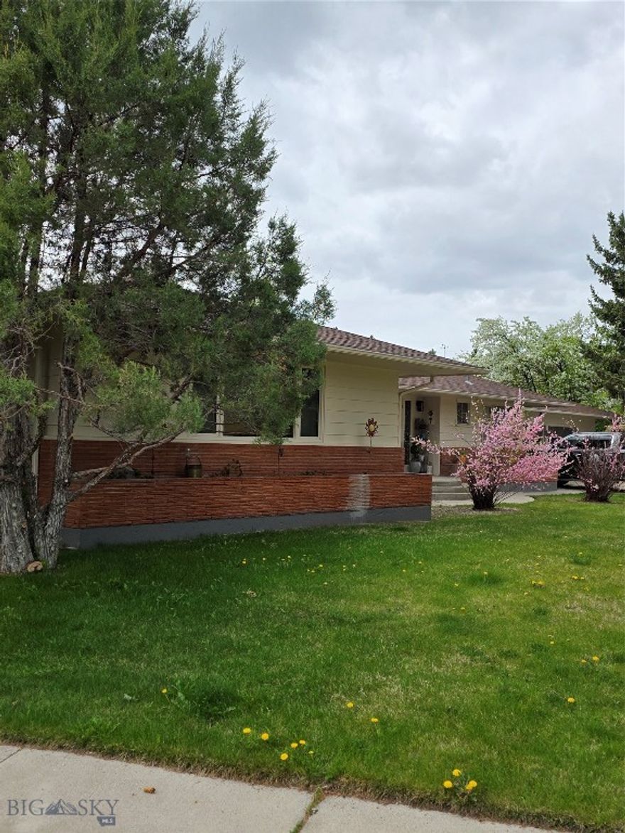 Open the door to this spacious mid century modern home at 606 S Arizona Street on a fully landscaped corner lot near UM Western.  Step in one of three birch outside doors and marvel at the craftsman and character of this well constructed home.  The large eat-in kitchen boast birch cabinets, updated counter tops and back splash, newer appliances, and a pet feeding station.  Meander down the hall past a 1/2 bath to a row of storage and coat closets. The comfortable living area features several build-ins to display your keepsakes , a large picture window , and new carpet. The primary bedroom has custom closets and a retro-vibe tiled en-suite bathroom. Two additional bedrooms , a bathroom with accessible shower and tons of storge are situated off the living area. Enjoy the Sunroom with over 40' of windows facing the fenced back yard.  A pass- thru window to the kitchen offers ease for entertaining. A newly renovated basement with 1500s.f.  lends itself to multi generational living, short term rental or extra space for a large family. Two basement bedrooms are non-comforming. All rooms, bedrooms, bathroom, kitchen, laundry and storage are accessible through the garage or the main floor living room.  Property has an attached 3 car garage with 2 storage rooms and a work bench.  The outside brick planters, UGS and mature trees provide privacy and ease of maintenance.