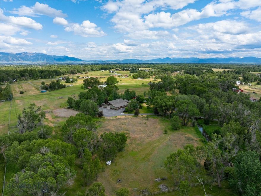 THREE DWELLINGS, 11+ ACRES, TWO SHOPS, NO ZONING, LIVE WATER & LIMITLESS OPPORTUNITY. This multi-family compound is situated on 11.5 acres with the beautiful Baker Creek flowing through, incredible Bridger Mountain Views, huge equipment storage, and lush livestock pastures. The main house includes 3 bedrooms, 2 bathrooms, dedicated office space, multiple flex rooms perfect for in home gyms, game rooms, dens and more. Upstairs, there is a large and comfortable 2 bedroom, 1 bathroom, fully appointed apartment with it's own private entrance. The attached shop space is unparalleled, with a heated 3,250 sqft complete with a full kitchen, bathroom, built-in storage, attached additional workshop, and drain system. If that storage space isn't enough, also included is an additional detached, 1,092 sqft shop and two more additional garage spaces. The 5 star level 10 Exceptional Rated guest cabin, affectionally known as the "Cabin Sweet Cabin" has been beautifully renovated boasting 3 bedrooms, 3 bathrooms, a loft, covered patios, hot tub and more. Currently used as an extremely successful vacation rental, the guest cabin is sold beautifully furnished and turn key as an income producing property. There are minimal covenants and no HOA here. This property was formerly home to a large scale construction company and promotes itself so well to live/work opportunities, while simultaneously offering guest space and SUBSTANTIAL rental income production. This property could easily accommodate multi-generational living or serve as simply an incredible investment opportunity with several rental income avenues. Located at the very end of the road, bask in a quiet, rural setting with fenced livestock pastures, chicken coops, firepit, irrigated garden areas, a beautiful creek that attracts regular local wildlife, mature trees, and a Bridger Mountain backdrop. This home is truly unique and provides soo many opportunities that are becoming increasingly difficult to find. Located off of Amsterdam road, your commute to Bozeman, Belgrade, Manhattan and the Bozeman Airport are a breeze. Let your imagination run wild and make this your dream HOME SWEET MONTANA HOME today!