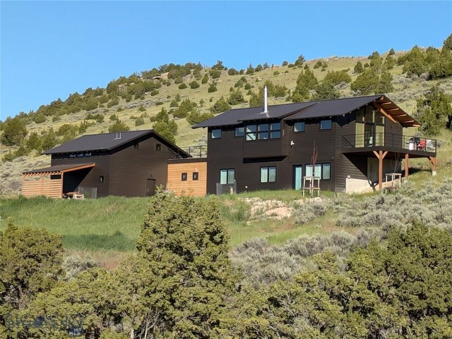 Welcome to Solstice House!  Built in 2022 and offering 2,705 square-feet on 20+ acres, this architectural showpiece was designed in the style of Northwest Modernism, popular since the midcentury for its connection to the outdoors, high livability, natural materials, and clean lines.  Three bedrooms and two baths with 9' ceilings comprise the ground level, while the pavilion-like upper level presents a grand living area with 360-degree views and a vaulted ceiling.  The primary architectural gesture is the alignment of the great room with sunrise on the summer solstice, giving the house its name.  With a large deck and patio to elevate the indoor/outdoor experience, horses grazing in the surrounding hills, buttes and ridges replete with wildlife, Big Sky sunsets, it's a tranquil place where evenings feel like weekends and weekends feel like escapes.  In support of the primary home, there's an ADU with a private entrance, the well log records an astounding 100 gallons per minute, and the property could easily support another home, barn, fenced pasture, and accessory buildings.  Located in Gallatin River Ranch, the vast 6,000-acre development is lifestyle-enhancing with two famous rivers, an impressive Equestrian Center, two riverside parks, and over 20 miles of private roads and trails great for hiking and biking.  Less than three miles from charming Manhattan, Mont., Solstice House is a 20-minute drive from the airport and 30 minutes to Bozeman's growing amenities.