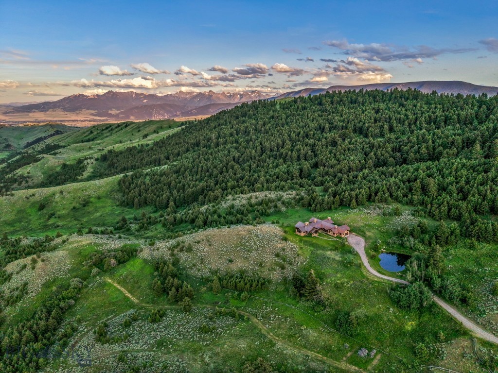 Sky Band Ranch, at the southern base of the Bangtail Mountains captures the magic of Southwestern Montana. Its location between the treasured towns of Bozeman and Livingston makes it even more desirable. The ranch spans +/- 262 serene acres offering the freedom to mountain bike, hike, horseback ride, hunt, snowshoe or cross-country ski right out the back door. It supports horses or other livestock. Area Creek (also known as O’Rea Creek) runs on the ranch for approximately 1/3 mile. The gorgeous western-style residence and pond are tucked upon a hilltop bordered by timbered hillsides, lush meadows and creek bottom providing refuge to elk, deer, moose, bear, grouse, Hungarian partridge, and other impressive wildlife. The residence built in 2008 exemplifies exceptional craftsmanship and meticulous attention to detail, effortlessly combining rustic style with attractive finishes perfectly integrated into the striking Montana landscape. Massive amounts of stone were brought in for the outdoor patio area, some interior and exterior walls, and five substantial fireplaces. Hewn Douglas fir was used for the interior and exterior walls. Custom made cabinetry, solid wood doors, trim and gorgeous wide plank fir flooring which has been recently refinished to perfection are found throughout the main floor. Pella windows and French doors frame the beautiful landscape of mostly ranch land with the Absaroka Mountains as its backdrop. Massive wood beams/trusses and impressive two-sided stone fireplace anchor the sun filled open floor plan of the living/kitchen/dining area creating a wonderful lodge atmosphere for gatherings or hunkering down with an enjoyable book. Additionally, there is a dedicated office/library, a spacious laundry room, and an oversized attached two-car garage. Downstairs is a 4,758 sf partially finished walk out basement offering endless possibilities. The property is behind a locked gate. This may be an excellent candidate for a conservation easement. Sky Band Ranch offers an extraordinary Montana lifestyle for outdoor enthusiasts seeking stunning views, open space and nature near world-class amenities.