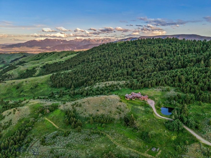 Sky Band Ranch, at the southern base of the Bangtail Mountains captures the magic of Southwestern Montana. Its location between the treasured towns of Bozeman and Livingston makes it even more desirable. The ranch spans +/- 262 serene acres offering the freedom to mountain bike, hike, horseback ride, hunt, snowshoe or cross-country ski right out the back door. It supports horses or other livestock. Area Creek (also known as O’Rea Creek) runs on the ranch for approximately 1/3 mile. The gorgeous western-style residence and pond are tucked upon a hilltop bordered by timbered hillsides, lush meadows and creek bottom providing refuge to elk, deer, moose, bear, grouse, Hungarian partridge, and other impressive wildlife. The residence built in 2008 exemplifies exceptional craftsmanship and meticulous attention to detail, effortlessly combining rustic style with attractive finishes perfectly integrated into the striking Montana landscape.  Massive amounts of stone were brought in for the outdoor patio area, some interior and exterior walls, and five substantial fireplaces. Hewn Douglas fir was used for the interior and exterior walls. Custom made cabinetry, solid wood doors, trim and gorgeous wide plank fir flooring which has been recently refinished to perfection are found throughout the main floor. Pella windows and French doors frame the beautiful landscape of mostly ranch land with the Absaroka Mountains as its backdrop. Massive wood beams/trusses and impressive two-sided stone fireplace anchor the sun filled open floor plan of the living/kitchen/dining area creating a wonderful lodge atmosphere for gatherings or hunkering down with an enjoyable book. Additionally, there is a dedicated office/library, a spacious laundry room, and an oversized attached two-car garage. Downstairs is a 4,758 sf partially finished walk out basement offering endless possibilities.  The property is behind a locked gate. This may be an excellent candidate for a conservation easement. Sky Band Ranch offers an extraordinary Montana lifestyle for outdoor enthusiasts seeking stunning views, open space and nature near world-class amenities.