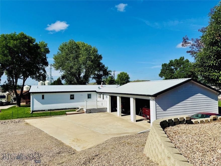 From the moment your wheels crunch along the graveled driveway and transition onto the smooth concrete leading to the three-stall garage, it’s clear—this property is truly special. Set on a generous 0.771-acre parcel, the home offers a rare combination of privacy and comfort. Inside, the three-bedroom, two-bathroom residence is immaculate. Each room flows seamlessly into the next, creating a harmonious and welcoming interior. Step outside, and you’re transported into what feels like a storybook oasis. Lush green grass and beautifully maintained landscaping surround a screened-in "she-shed”, a perfect retreat for playing games, enjoying a morning coffee, or relaxing with evening drinks in the fresh Montana air, all without the bother of pests. A separate lawn shed keeps all yard tools and the mower neatly stored, while a dedicated workshop behind the she-shed is ideal for woodworking or hobbies. A concrete pad provides easy, secure parking for a camper or boat. Enjoy gardening in the serene backyard, where a charming water tower feature adds a peaceful ambiance with the sound of trickling water. The home is turnkey, with a complete list of accompanying items available upon request. There is even a bomb shelter below the detached garage. Need another building or looking to invest and profit? Lots 4, 5, and 6 of the property have separate water, sewer, and gas services, which are currently unused. Conveniently located just 40 miles from Great Falls and its international airport, this pristine property has been lovingly maintained and thoughtfully updated, offering the rare chance to enjoy years of effort and care from the moment you arrive.
