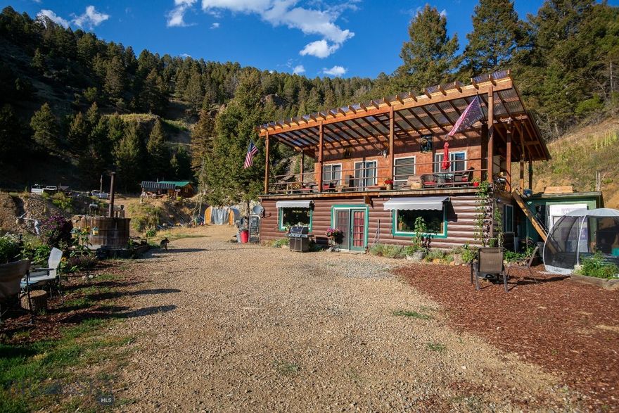 Step back in time and discover a retreat unlike any other. Tucked away outside the charming town of Sheridan, Montana, the Fairview Mine Retreat offers more than 33 acres of history, beauty, and possibility. Bordered by thousands of acres of BLM and Forest Service land, this property blends the spirit of Montana’s pioneering past with the tranquility of an off-grid hideaway. The main cabin, thoughtfully designed at 1,696± square feet, features a main level with welcoming kitchen and dining area, cozy living room with wood-burning stove, mine-themed bar, and bathroom with storage and laundry. Upstairs, you’ll find a bedroom with ensuite bath, a library-style living space, and a large deck overlooking the surrounding landscape. Step outside to enjoy a wood-heated hot tub with sweeping views of the valley, mountains, and endless wilderness. A second cabin of 576± square feet offers a bedroom, full bath, spacious kitchen and living area, and a covered porch. Both cabins are powered by independent solar systems, providing comfort in a truly self-sufficient setting. At the heart of the property is the Fairview Mine itself — a rare opportunity to own a piece of Montana’s mining history. Complete with historical mining equipment and an assay testing building, the mine is more than a landmark. It is a story to be preserved, explored, and treasured. Whether appreciated as a heritage site or embraced by those with a pioneering spirit, this feature sets the property apart as truly one of a kind. Private, serene, and brimming with character, the Fairview Mine Retreat invites adventurers, historians, and dreamers to carry forward a remarkable Montana legacy. Property to be sold furnished with historical mining equipment conveying.