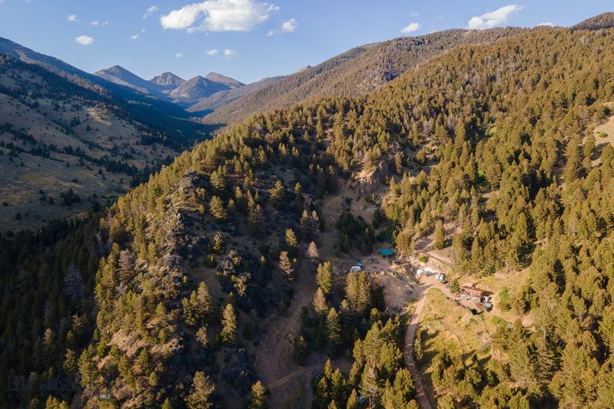 Step back in time and discover a retreat unlike any other. Tucked away outside the charming town of Sheridan, Montana, the Fairview Mine Retreat offers more than 33 acres of history, beauty, and possibility. Bordered by thousands of acres of BLM and Forest Service land, this property blends the spirit of Montana’s pioneering past with the tranquility of an off-grid hideaway. The main cabin, thoughtfully designed at 1,696± square feet, features a main level with welcoming kitchen and dining area, cozy living room with wood-burning stove, mine-themed bar, and bathroom with storage and laundry. Upstairs, you’ll find a bedroom with ensuite bath, a library-style living space, and a large deck overlooking the surrounding landscape. Step outside to enjoy a wood-heated hot tub with sweeping views of the valley, mountains, and endless wilderness. A second cabin of 576± square feet offers a bedroom, full bath, spacious kitchen and living area, and a covered porch. Both cabins are powered by independent solar systems, providing comfort in a truly self-sufficient setting. At the heart of the property is the Fairview Mine itself — a rare opportunity to own a piece of Montana’s mining history. Complete with historical mining equipment and an assay testing building, the mine is more than a landmark. It is a story to be preserved, explored, and treasured. Whether appreciated as a heritage site or embraced by those with a pioneering spirit, this feature sets the property apart as truly one of a kind. Private, serene, and brimming with character, the Fairview Mine Retreat invites adventurers, historians, and dreamers to carry forward a remarkable Montana legacy. Property to be sold furnished with historical mining equipment conveying.