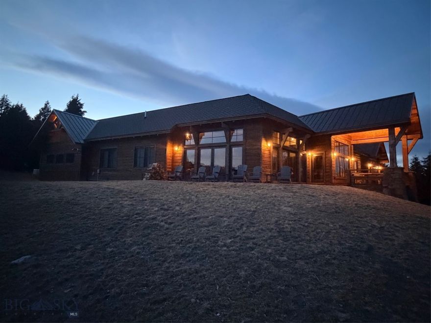 Rare opportunity to own an upper-end custom home on one of the most desirable lots in Sun West Ranch, where homes seldom come to market. This thoughtfully designed 4BR/4.5BA residence offers approximately 3,745± square feet and is perched to capture wide-open, unobstructed views across conservation ranchland and surrounding mountain ranges.
An open-concept layout is complemented by a separate living room anchored by an impressive stone, wood-burning fireplace. Mountain-rustic finishes are elevated with dark timber beams, white-washed tongue-and-groove ceilings, and expansive Marvin windows and doors. Two decks and a stamped concrete patio extend living space outdoors, creating a strong connection to the natural surroundings.
The kitchen features GE Café appliances, double ovens, and a gas cooktop. The main level primary suite includes a propane fireplace with a natural Montana stone mantle and stunning views. Two main level guest rooms have private baths. A second primary suite on the lower level provides exceptional privacy.  The residence is offered fully furnished with high-quality and custom pieces for immediate enjoyment.
The 4.353-acre lot is covered with mature Douglas fir trees, limbed up for fire prevention and a park-like setting. The property borders ranch open space with nearby access to National Forest and Standard Creek, ensuring permanently protected views and privacy.
Additional features include a finished, insulated, and heated three-bay garage stubbed for EV charging, a 75 SF secure room for valuables, Generac backup power with remote monitoring, fiber optics, on-demand hot water, water filtration, oversized cistern, underground irrigation, and monitored security and alarm systems.
Sun West Ranch is a gated 2,000-acre community with approximately 1,600 acres of open space, two miles of Madison River frontage, stocked ponds, and equestrian amenities. Homes may be used as vacation rentals between May and October. Conveniently located near Yellowstone National Park, Big Sky Resort, and regional and private air access.