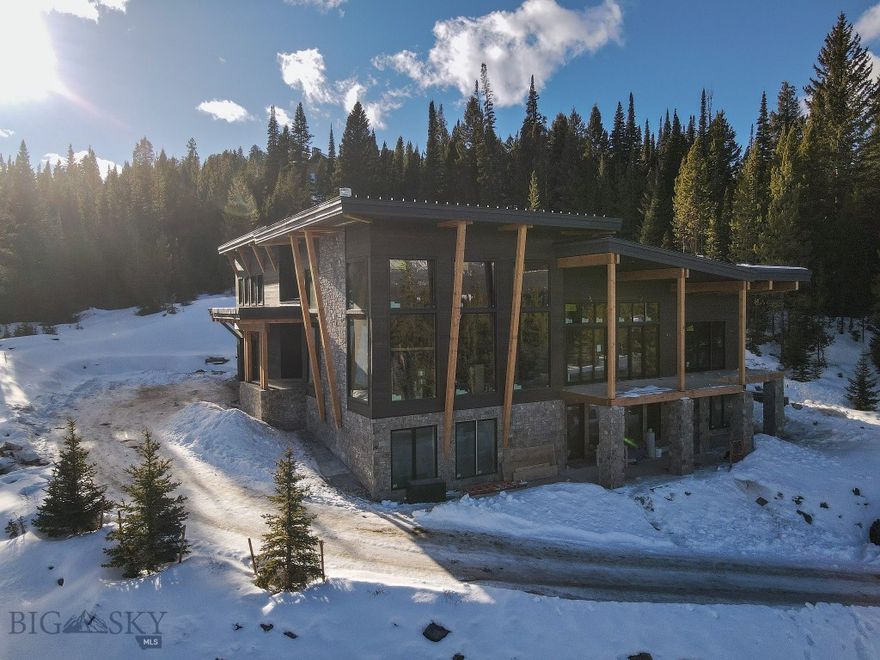 Set amidst the grandeur of Big Sky’s Spanish Peaks Mountain Club, this extraordinary home is a modern mountain sanctuary where architecture and landscape live in perfect harmony. From the moment you step inside, walls of floor-to-ceiling windows frame sweeping, unobstructed views of the Spanish Peaks mountain range, flooding each room with golden Montana light and an ever-changing panorama of alpine beauty.

Designed for both relaxation and recreation, the residence features five spacious bedrooms and six and a half baths, offering luxurious comfort for family and guests alike. The heart of the home is a grand great room anchored by a handcrafted stone fireplace, where evenings unfold in warmth and style. The wine room, with its 17-foot ceilings, creates a signature space just off the great room, while the indoor sauna provides the perfect retreat after a day of skiing or hiking.

For those with an active spirit, there is a private sport court designed and built for regulation pickleball along with a basketball hoop, hockey nets or workout area -  opportunities abound for your needs. The trail system is just steps from the back door and offer endless choices for play and exploration. Enjoy the Tom Weiskopf golf course or the Tom’s 10 Par 3 Course. The Spanish Peaks Club house offers fine dining, clubhouse bar, golf/ski shop, fitness center and pool/hot tub. Expansive outdoor living spaces — including a large patio with kitchen out back and a covered deck out front — create an effortless flow between the indoors and Montana’s magnificent outdoors.

Only a short drive from Big Sky’s Town Center, this residence combines refined design, thoughtful amenities, and a deep connection to nature. It’s more than a home — it’s a lifestyle defined by serenity, adventure, and the unmatched beauty of the Spanish Peaks. Scheduled completion spring 2026.