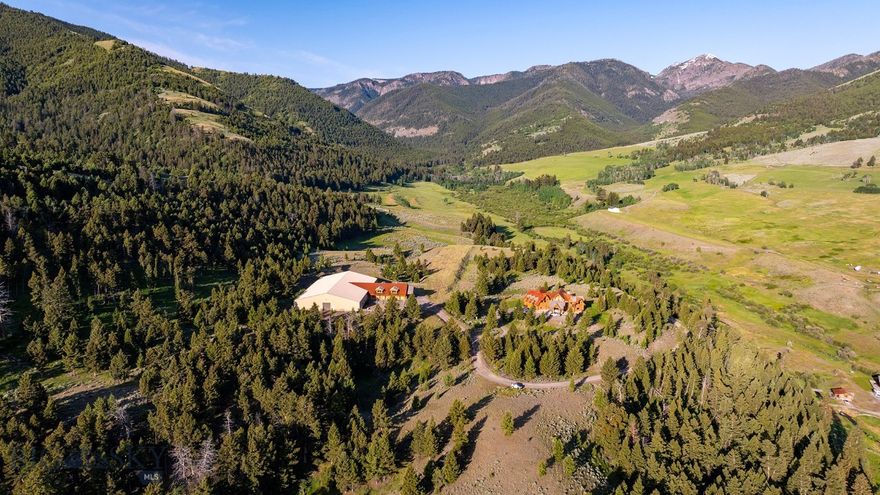 Step into a world straight out of “Legends of the Fall” on this breathtaking 86+/- acre property nestled deep within Montana’s pristine Cinnabar Basin. As you pass through the entryway arch, your eyes will delight in their surroundings  and you will feel as though you have been transported to another world—one where life is as peaceful as the creek babbling throughout the property. Just minutes from Yellowstone National Park, this private mountain retreat offers a rare opportunity to own a slice of the American West which most can only see on television. This remarkable Cinnabar Basin sanctuary was originally settled by one of the first ranching families to arrive in Paradise Valley in the 1800’s, and now it can be yours.
The main lodge features a magnificent 4379 sqft (basement sqft excluded) primary residence including a grand entrance opening to a living area framed by massive windows and showcasing unparalleled views. As you move to the left, you will find a rustic yet thoughtfully designed gourmet kitchen, inviting communion with its gorgeous finishes and large welcoming island. Ascend the curved staircase to the second floor and an oversized hallway leads you to multiple bedrooms and bathrooms, providing ample space for overnight guests.
Three cabins are scattered throughout the property and could be utilized as rentals or a family compound.
Just a short walk from the main home, and at the property’s highest point, you will find a world-class riding arena with beautifully crafted stables and newly finished living quarters. This area of the property also includes an airstrip which lies near the arena, once used for landing small aircraft. Downhill and private from the primary residence rests a log-sided barn suitable for storage, a workshop, or conversion to an additional living quarters. Located just 30 minutes from Gardiner and 80 minutes from Livingston, this retreat offers both seclusion and accessibility. There are plenty of amenities nearby so you will never run out of activities to enjoy! Whether you’re seeking a permanent residence, a multi-generational family compound, or an exclusive vacation getaway with rental potential, this property has it all. Here, you will enter an unparalleled living experience where the spirit of the West is thriving.