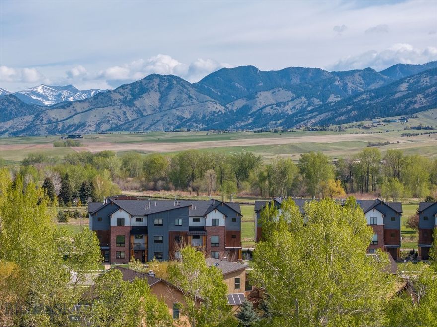 Framed by open green space with protected Bridger Mountain views, this modern 4-bedroom, end-unit townhome offers rare unobstructed Montana views and natural light just minutes from downtown Bozeman. Glen Lake Rotary Park sits directly across the street, offering a scenic lake for summer swimming and winter ice fishing, along with picnic tables and expansive open space.  The ground level features an oversized two-car garage, a flexible office suite or fourth bedroom, a full bath, and a welcoming entry. The second floor opens to a bright, contemporary living space where expansive glass sliders frame the mountains and create seamless indoor-outdoor flow. The kitchen is designed for both everyday function and entertaining, anchored by a waterfall quartz island, 36-inch gas range, walk-in pantry, and clean, modern finishes. Upstairs, a dedicated laundry room, additional en-suite bedroom, and a spacious primary suite provide separation and privacy. The primary retreat includes a gas fireplace and a well-appointed bath, creating a comfortable space to unwind.  Multiple balconies extend the living experience outdoors, capturing views of the surrounding open space and mountains. Located in Bridger Vale with REMU zoning, the property also allows flexibility for certain live/work opportunities.  With immediate access to trails, open space at your doorstep, and downtown Bozeman just minutes away, this residence offers a balanced blend of location, design, and long-term view protection.