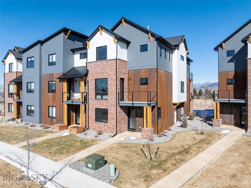 Framed by open green space with protected Bridger Mountain views, this modern 4-bedroom, end-unit townhome offers rare unobstructed Montana views and natural light just minutes from downtown Bozeman. Glen Lake Rotary Park sits directly across the street, offering a scenic lake for summer swimming and winter ice fishing, along with picnic tables and expansive open space.  The ground level features an oversized two-car garage, a flexible office suite or fourth bedroom, a full bath, and a welcoming entry. The second floor opens to a bright, contemporary living space where expansive glass sliders frame the mountains and create seamless indoor-outdoor flow. The kitchen is designed for both everyday function and entertaining, anchored by a waterfall quartz island, 36-inch gas range, walk-in pantry, and clean, modern finishes. Upstairs, a dedicated laundry room, additional en-suite bedroom, and a spacious primary suite provide separation and privacy. The primary retreat includes a gas fireplace and a well-appointed bath, creating a comfortable space to unwind.  Multiple balconies extend the living experience outdoors, capturing views of the surrounding open space and mountains. Located in Bridger Vale with REMU zoning, the property also allows flexibility for certain live/work opportunities.  With immediate access to trails, open space at your doorstep, and downtown Bozeman just minutes away, this residence offers a balanced blend of location, design, and long-term view protection.