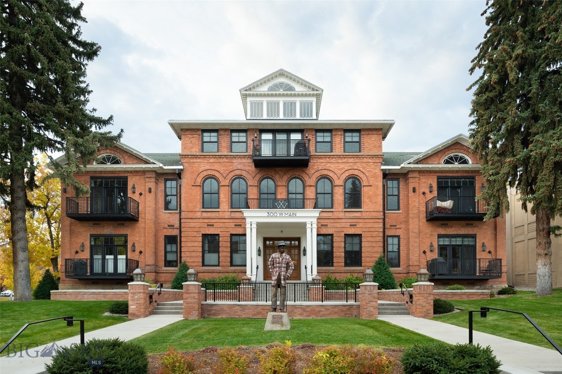 There’s ordinary downtown living, and then there’s downtown living at its finest: The Willson Residences. Heralded as a masterpiece when the Bozeman landmark’s exterior was restored and reimagined in 2015-2017 and the 1903 and 1913 interiors fully transformed into 16 new condominiums, each one-of-a kind and artfully planned to capture urban functionality, contemporary comfort, and historical character.
This stunning Willson Residence is offered fully furnished including all art, rugs & furniture. Located in the center of vibrant downtown Bozeman, yet with the unique privacy of a surrounding large lawn and century old trees, the Willson Residence’s G shows better than new as G as only been occupied occasionally since its completion in 2016. This highly sought-after east facing unit captures the views of the stained-glass windows across the street and features the ease of one level living with walls of windows overlooking large private decks. Its spectacular interior was entirely customized with modern light fixtures, specially chosen tile & an epicure’s kitchen featuring Thermador appliances and an island with ample seating. Two true (non-loft) bedrooms, located on opposite ends of the condo ensure maximum privacy and comfort. The primary bedroom suite is highlighted by a private patio, and a capacious bathroom with both a tiled steam-shower and free-standing tub. This unit includes a private, secure, heated parking garage with elevator access, with a 1-car assigned parking space and locked, storage unit.