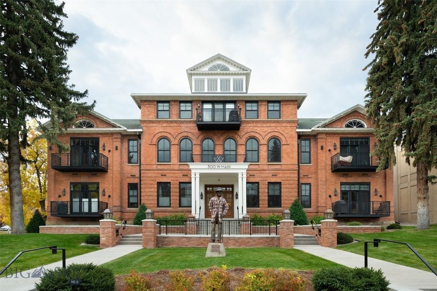 There’s ordinary downtown living, and then there’s downtown living at its finest: The Willson Residences. Heralded as a masterpiece when the Bozeman landmark’s exterior was restored and reimagined in 2015-2017 and the 1903 and 1913 interiors fully transformed into 16 new condominiums, each one-of-a kind and artfully planned to capture urban functionality, contemporary comfort, and historical character.
This stunning Willson Residence is offered fully furnished including all art, rugs & furniture. Located in the center of vibrant downtown Bozeman, yet with the unique privacy of a surrounding large lawn and century old trees, the Willson Residence’s G shows better than new as G as only been occupied occasionally since its completion in 2016. This highly sought-after east facing unit captures the views of the stained-glass windows across the street and features the ease of one level living with walls of windows overlooking large private decks.  Its spectacular interior was entirely customized with modern light fixtures, specially chosen tile & an epicure’s kitchen featuring Thermador appliances and an island with ample seating. Two true (non-loft) bedrooms, located on opposite ends of the condo ensure maximum privacy and comfort. The primary bedroom suite is highlighted by a private patio, and a capacious bathroom with both a tiled steam-shower and free-standing tub. This unit includes a private, secure, heated parking garage with elevator access, with a 1-car assigned parking space and locked, storage unit.