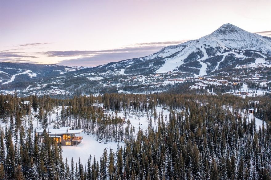 As you approach this mountain modern family home, designed by renowned Bozeman architect, Reid Smith, you will feel the unique privacy afforded by this spacious 2.1-ac forested lot. The house is built to the highest standards by long-time established, Big Sky Build, and is positioned to maximize the down-valley views looking west.  Enter the home through the custom-designed, 9' door made from a live-edged, slab of center-cut walnut, and you will be struck by the unique proportions and flow of the home. Ideal for entertaining family and friends, the upper floor common area flows from the true chef's kitchen to the intimate dining area to a glass-encased living room. The award-winning Gyrofocus fireplace is a focal point of the living room, suspended from the cedar-lined ceiling as it rises to 17'. The impressive views will have you mesmerized by the sunsets from the outdoor living/dining/grilling area with a gas fire bowl. The sleek & functional kitchen is centered around a large island, encased in honed Brazilian marble that waterfalls at either end with a large Subzero fridge, 2 Wolf wall ovens, and a Wolf cooktop range. Custom-designed walnut cabinetry provides extensive storage & a pantry area with a coffee station. The wide staircase flows down to the lower family room with generous space to relax, watch movies, or exercise, the bunk room, an additional bedroom, and the spacious second master suite. Walk out to a large patio area with a gas fire pit and hot tub and overlook the magnificent Spanish Peaks. The large laundry room has a walk-in storage area with double doors & a lock-off. The upper level master suite is a true masterpiece, with a gas fireplace and an en suite with a generous shower area and freestanding sculptural tub, adjacent to a walk-in closet with custom built-ins. The house is visually anchored to the land by a custom, monolithic, pressed barn board, concrete axis wall that runs floor to ceiling inside and outside the home. The heated garage can house 2 full-size SUVs, firewood, ski racks, & boot heaters. Adjacent to but high above the exclusive Ulery's Lake parcels in Moonlight Basin, the property offers quick access to Lone Mountain Trail and a 3-minute drive to both Moonlight and LakeLodge. Alternatively, ski access is a short walk to the Cascade ski access trails both in & out. This home has been thoughtfully designed & positioned to integrate into the magnificent landscape of Big Sky while taking advantage of natural light.