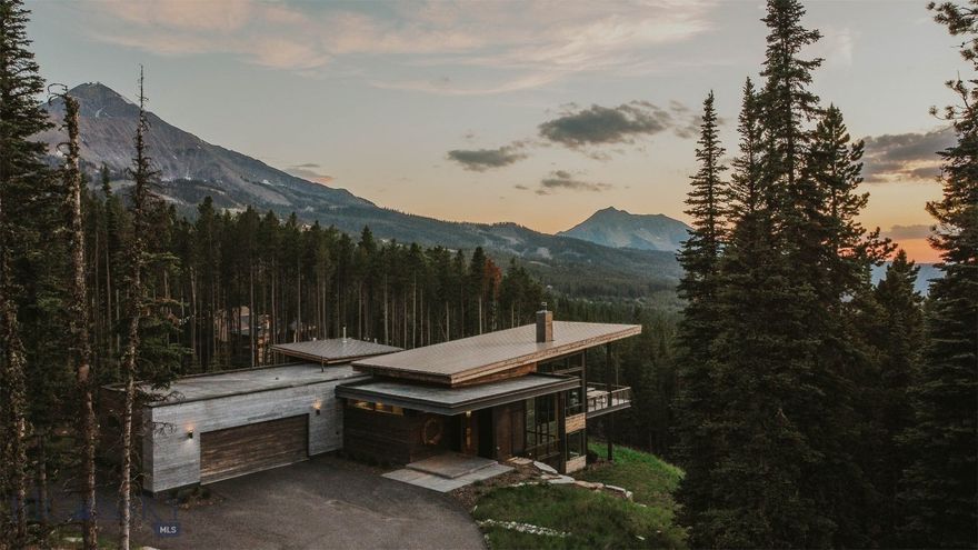 As you approach this mountain modern family home, designed by renowned Bozeman architect, Reid Smith, you will feel the unique privacy afforded by this spacious 2.1-ac forested lot. The house is built to the highest standards by long-time established, Big Sky Build, and is positioned to maximize the down-valley views looking west.  Enter the home through the custom-designed, 9' door made from a live-edged, slab of center-cut walnut, and you will be struck by the unique proportions and flow of the home. Ideal for entertaining family and friends, the upper floor common area flows from the true chef's kitchen to the intimate dining area to a glass-encased living room. The award-winning Gyrofocus fireplace is a focal point of the living room, suspended from the cedar-lined ceiling as it rises to 17'. The impressive views will have you mesmerized by the sunsets from the outdoor living/dining/grilling area with a gas fire bowl. The sleek & functional kitchen is centered around a large island, encased in honed Brazilian marble that waterfalls at either end with a large Subzero fridge, 2 Wolf wall ovens, and a Wolf cooktop range. Custom-designed walnut cabinetry provides extensive storage & a pantry area with a coffee station. The wide staircase flows down to the lower family room with generous space to relax, watch movies, or exercise, the bunk room, an additional bedroom, and the spacious second master suite. Walk out to a large patio area with a gas fire pit and hot tub and overlook the magnificent Spanish Peaks. The large laundry room has a walk-in storage area with double doors & a lock-off. The upper level master suite is a true masterpiece, with a gas fireplace and an en suite with a generous shower area and freestanding sculptural tub, adjacent to a walk-in closet with custom built-ins. The house is visually anchored to the land by a custom, monolithic, pressed barn board, concrete axis wall that runs floor to ceiling inside and outside the home. The heated garage can house 2 full-size SUVs, firewood, ski racks, & boot heaters. Adjacent to but high above the exclusive Ulery's Lake parcels in Moonlight Basin, the property offers quick access to Lone Mountain Trail and a 3-minute drive to both Moonlight and LakeLodge. Alternatively, ski access is a short walk to the Cascade ski access trails both in & out. This home has been thoughtfully designed & positioned to integrate into the magnificent landscape of Big Sky while taking advantage of natural light.