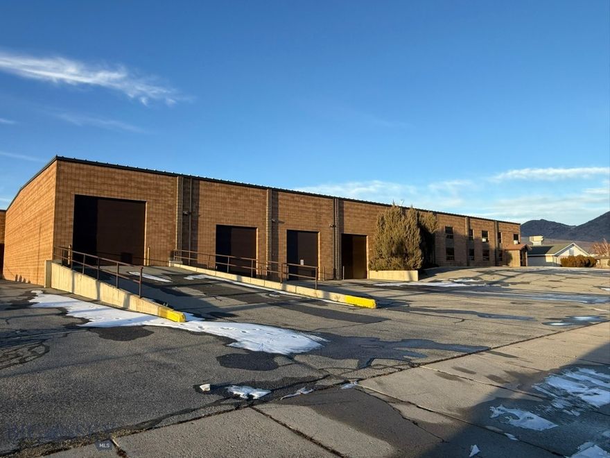 This large industrial warehouse is centrally located in the Butte Warehouse District, originally constructed in 1990 for a beer and wine distribution business. The facility features durable cement block construction, complemented by a metal roof and steel truss system. Office spaces are equipped with hot water heating, while both the warehouse and offices benefit from heating and air conditioning systems.
The warehouse encompasses approximately 22,940 square feet, with an adjoining office area of roughly 5,000 square feet. Key amenities include two semi loading docks, three industrial overhead doors, and one bay door with a drive-in ramp for direct warehouse access. The property boasts approximately 20-foot ceilings, a cooler, substantial storage capacity, and a two-story office suite comprising a spacious reception area, walk-in safe, five main-floor offices, executive offices on the upper level, a large conference room, and three restrooms—two of which have showers. The property is owned by the listing Broker.
Additional features include four separate exits, parking accommodations for 27 vehicles with supplementary space available in the yard, and three-phase electrical service. This property is currently owned by the listing broker.