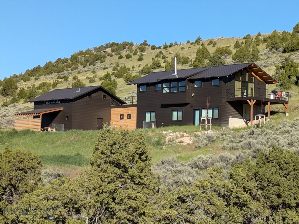 Welcome to Solstice House outside Manhattan, Montana, presented by Blake Maxwell at Skyfarm Design+Build. With amazing views of buttes and rolling prairie, this architectural home on over 20 acres was designed in the style of Northwest Modernism, popular since the midcentury for its floor-to-ceiling windows, natural materials, clean lines, high livability, and connections to the outdoors. Built in 2022 and offering 2,705 square feet, the interiors favor coherence and calmness. Three bedrooms and two baths comprise the ground level, while the pavilion-like upper level presents an open floorplan to engage the landscape. Two large decks further blur the boundary between living areas and the outdoors. With horses grazing on a nearby hillside, Big Sky sunsets, and the comfiness of a beach house, it’s a tranquil place where evenings feel like weekends and weekends seem like getaways. The primary architectural gesture is the alignment of the great room with sunrise on the summer solstice--June 21st this year--giving the house its name (see last photo). In addition, there's an ADU/studio with a separate entrance, kitchenette and ½ bath. Also, the private well was recorded producing 100 gallons per minute of water, which could easily support a guest house, greenhouse, livestock barn or pasture. Located on the Gallatin River Ranch, the vast 6,000-acre development is lifestyle-enhancing with two Montana rivers, over 20 miles of private roads great for hiking and biking, and an impressive Equestrian Center. It's also home to elk, mule deer, pronghorn, coyotes, dozens and dozens of bird species. Less than three miles from charming Manhattan, Solstice House is a 20-minute drive to BZN airport and 30 minutes to Bozeman’s numerous amenities.