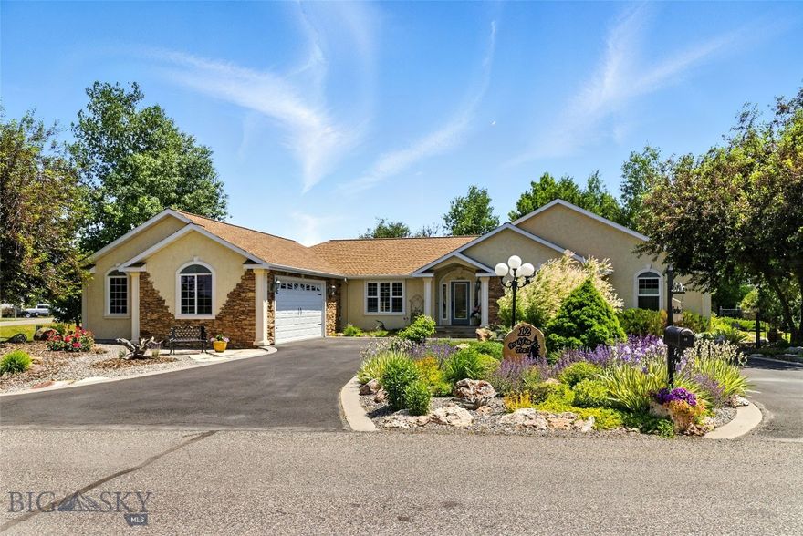 Better than new, this 2,695± sq ft custom home in Valley Grove reflects thoughtful design, quality craftsmanship, and exceptional care throughout. Set on a beautifully maintained 0.65± acre corner lot, the property is framed by mature landscaping and a private backyard retreat featuring stone-edged garden beds, expansive stone patios and walkways, and a 20-zone underground sprinkler system. Inside, the single-level floor plan is both elegant and functional, highlighted by vaulted ceilings, rich hardwood floors, and refined architectural details. Marble window and door casings, custom woodwork, and carefully selected finishes elevate every space. The kitchen anchors the home with solid-surface granite countertops, an antique-style island, and custom cabinetry, flowing naturally into a comfortable dining area ideal for everyday living. A nearby formal dining or sitting room, accented by classic columns and travertine details, offers a more refined setting for entertaining or quiet conversation. The living room serves as a welcoming centerpiece, featuring a gas fireplace with a tiled mantle, live-edge wood accents, and abundant natural light. The home includes two primary suites, each with a private, well-appointed bath. All three bedrooms feature French doors that enhance the home’s timeless aesthetic while filling each room with light. The third bedroom—currently used as an office—includes reinforced built-in shelving designed for display of substantial artwork or collections. Each bathroom is thoughtfully designed with antique-style vanities and period-inspired mirrors, adding character and warmth to daily routines. The home has been lightly lived in, meticulously maintained, and consistently updated, offering true move-in-ready condition. Additional features include an attached, oversized two-car garage with a built-in hobby or storage room, along with a backyard shed providing flexibility for gardening or storage needs. Located in Valley Grove, one of Bozeman’s most established communities, residents enjoy access to a neighborhood park, pond, and volleyball court—just minutes from downtown Bozeman, Montana, Montana State University, and major commuter routes. A rare opportunity to own a home where timeless design meets everyday ease in an exceptional setting.