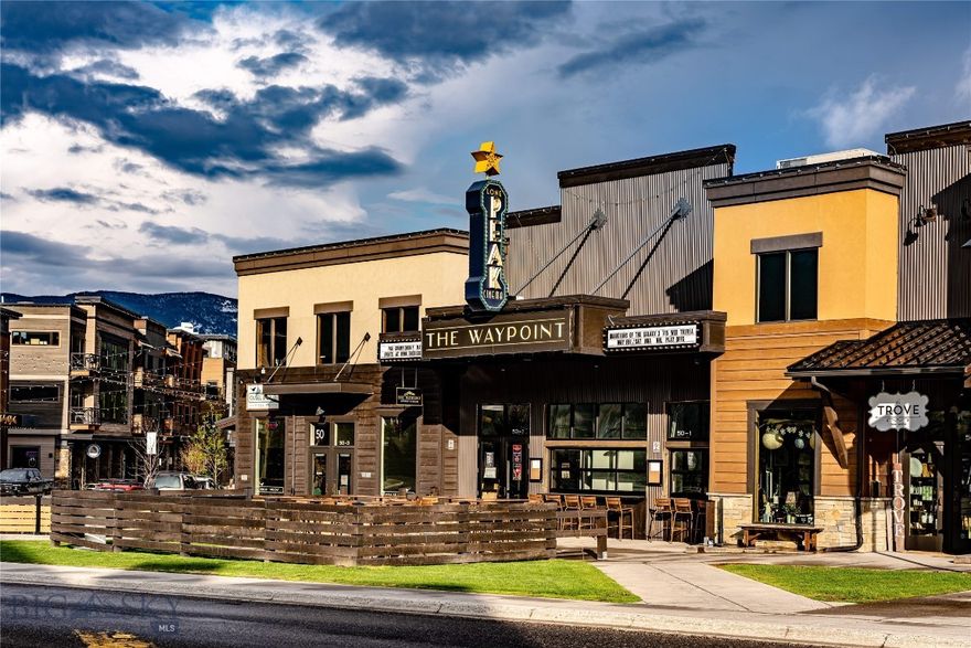 Situated on the most visible and high-traffic corner in Big Sky’s Town Center, 50 Ousel Falls Road offers a rare opportunity to invest in one of the community’s premier commercial buildings. Spanning over 9,000 square feet across three units, this property is fully leased to long-term tenants, including three of Big Sky’s most recognized and established businesses — Ousel & Spur Pizza Co., the Waypoint, and Trove — ensuring strong rental income and long-term stability. The property features two expansive, sun-filled patios that create vibrant outdoor gathering spaces, extending valuable seating for tenants and customers alike. The Waypoint, Big Sky’s only movie theater and a popular event venue, also includes a walk-up bar serving drinks to the many pedestrians attending summer farmer’s markets, Music in the Mountains concerts, and other seasonal events. Together, these features create a dynamic, social environment that attracts consistent foot traffic year-round. Positioned along Ousel Falls Road, the main corridor connecting to Yellowstone Club and Spanish Peaks Mountain Club, this location offers unmatched exposure, signage opportunities, and visibility in the heart of Town Center. Surrounded by major hotel, retail, and community developments such as Hotel Free West, The Wilson Hotel, Gravity Haus, and BASE, the area continues to thrive as Big Sky’s vibrant commercial and cultural hub. With its prime location, strong tenant mix, and proven income stability, 50 Ousel Falls Road stands as one of the most desirable and enduring commercial investment opportunities in Big Sky — perfectly positioned for the town’s next phase of growth and development.