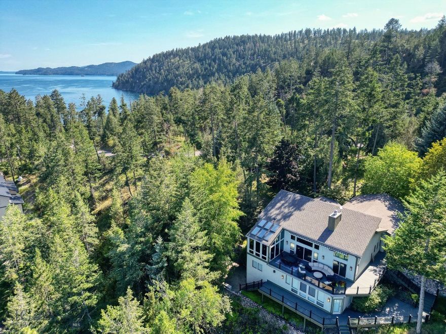 Perched above the sparkling waters of Flathead Lake, this extraordinary luxury estate offers sweeping views of the Swan Mountains & into Glacier National Park. Set on 2.67 private acres, on two lots with 251 ft. of pristine lake frontage, this property blends elegance, functionality, and Montana’s natural beauty. Every detail of this home has been thoughtfully enhanced with premium upgrades. A custom-designed funicular provides seamless access for all ages down to the water’s edge, where a beautifully upgraded dock system awaits, complete with a new hydraulic boat lift & a cantilever double PWC lift with interior catwalk. You will also find a mermaid pond at the water's edge. A charming nature pathway winds through the property, offering a scenic walk to the water. Outdoor living is unmatched with multiple sitting areas designed to take in the views, a cozy firepit for evening gatherings, and expansive decks-completely replaced and upgraded with glass railings to preserve the view. This home offers nearly 4,000 square feet of refined living space, including 5 bedrooms and 6 bathrooms, blending comfort and elegance with room for family and friends. The great room centers around a dramatic floor-to-ceiling river rock fireplace, with soaring vaulted ceilings that create a sense of grandeur and openness. The sunroom is a fan favorite among guests that have enjoyed it over the years, capturing year-round light and lake vistas. Wildlife carvings, including bears etched into the floor tiles, lend a bespoke, artistic touch that celebrates Montana’s wilderness spirit. Recent investments include a new HVAC system, boiler, furnace, paint, window treatments, two 24kW backup generators, and starlink high speed internet. A spacious attached triple garage provides convenience, while the separate heated shop offers ample space to store your boat, recreational gear, and seasonal toys. Fully equipped with a half bathroom, utility sink, and its own washer and dryer, the shop is designed with both functionality and comfort in mind—ideal for lake days, projects, or extended stays. Whether you're savoring the tranquil mountain vistas from the upper terrace, heading out for a day on the water, or simply unwinding in the serenity of your surroundings, this extraordinary Flathead Lake estate offers an unmatched retreat in the heart of Big Sky Country. This property is accessible year-round.