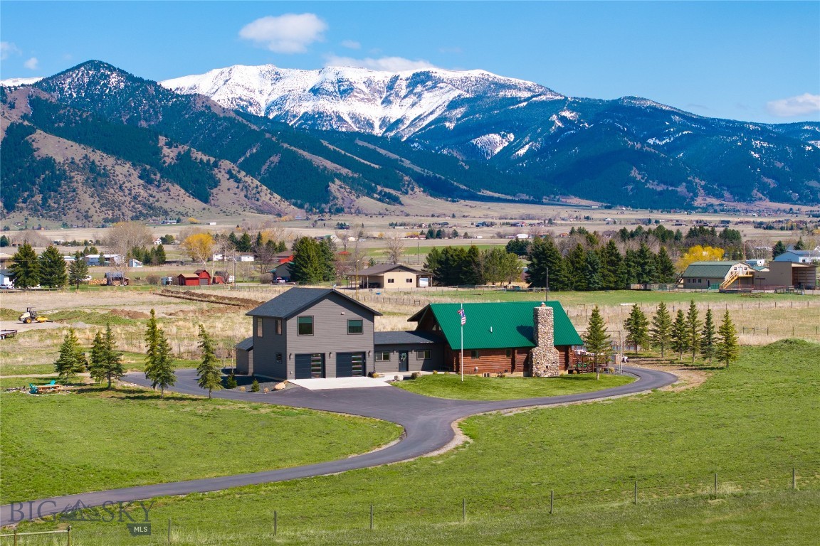 Nestled on 5 picturesque acres along Springhill, this property offers breathtaking, unobstructed views of the Bridger Mountains. Currently operating as two separate, successful vacation rentals. A truly unique offering, it features a beautifully refurbished log cabin, fully updated in 2020, alongside a modern 900 sq ft Accessory Dwelling Unit (ADU) built just four years ago. The ADU includes a two-car garage, a full kitchen, a bedroom, and a spacious full bathroom — ideal for guests, tenants, or multigenerational living.
Step inside the expansive 3,300+ sq ft log cabin and be welcomed by soaring vaulted ceilings and a sunlit, oversized main living room anchored by a charming wood-burning fireplace. Adjacent to the living room, you’ll find a newly renovated kitchen with contemporary finishes, as well as a full bathroom conveniently located near a cozy bedroom. Upstairs, a large loft-style primary suite awaits, complete with vaulted ceilings, a soaking tub, and a private walk-out balcony offering panoramic mountain views. The fully finished basement adds even more versatile living space, featuring a generous recreation room, an additional bedroom, a full bathroom, and an oversized closet and storage area. A bright sunroom connects the main cabin to the ADU garage, creating an ideal entryway, mudroom, or bonus storage space. Above the garage, the thoughtfully designed ADU apartment includes an open-concept living, dining, and kitchen area, a full bathroom, and a comfortable bedroom — all finished with modern touches. Both the cabin and the ADU are currently thriving as separate short-term rentals on Airbnb, offering excellent income potential. Outside, a paved wraparound driveway provides easy access and abundant parking, making it perfect for entertaining, hosting events, or simply accommodating multiple guests.