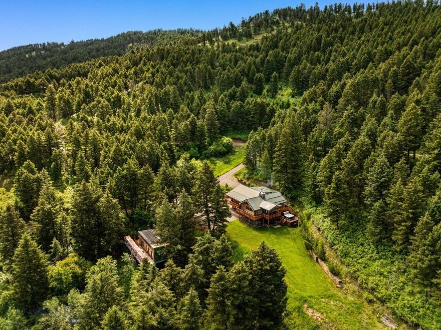 Welcome to the Cozy Alpine Chalet, a passionately handcrafted log home and legacy retreat, thoughtfully positioned on nearly 7 pristine private acres of alpine forest. Just 11 miles from both Bozeman and Livingston, and only 25 miles from Bozeman Yellowstone International Airport, the property offers effortless access to Montana’s finest dining, shopping, and outdoor adventure—yet feels like your own secluded mountain top forest escape, worlds away from it all. The main home has been extensively renovated between 2022 and 2025 with over $1 million in thoughtful upgrades including a full rebuild of mechanical systems, a smart home setup, professional interior styling, and high-end finishes throughout. Artisan log construction, natural wood and stone interiors, and over 30 Andersen windows bring in forest and mountain views from nearly every room, while six fireplaces create cozy gathering spaces indoors and out. This mountain retreat includes a chef’s kitchen with a full KitchenAid stainless steel suite, two laundry areas, and rich character in every detail. Tucked further into the trees, the Honeymoon Treehouse Villa is a newly built architectural jewel, elevated 15 feet above the forest floor. Built to Passive House / High-Performance standards, it features quadruple-pane glazing, premium insulation, and a future cantilevered hot tub deck, all framed by a soaring roofline designed for both elegance and energy efficiency. With all utilities installed and the interior ready for your finishing touch, this secondary structure offers limitless potential: a luxury rental, a serene guesthouse, or your personal creative retreat. This is a truly turn-key offering, with all furnishings, curated décor, bedding, chef’s cookware, and antiques included. Smart home features like Yale Wi-Fi locks, remote lighting and climate control, iPad/voice automation, and Starlink satellite internet ensure convenience and connectivity, even in this private setting. Whether you dream of taking over a luxury short term rental business (currently commanding up to $1300/night in the high season), creating a soulful family compound, or stewarding a rare legacy property for future generations…The Cozy Alpine Chalet awaits. With unmatched craftsmanship, immersive natural beauty, and an incredible location at the gateway to America’s first national park, this is truly Montana living at its finest.