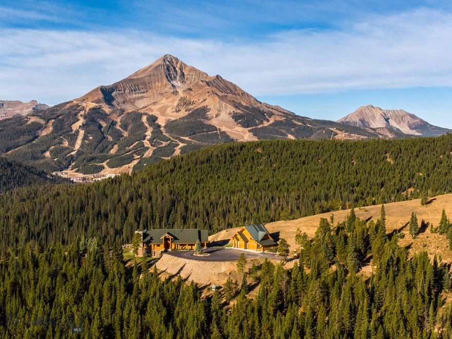 A once-in-a-lifetime opportunity in the heart of Big Sky, this 491-acre private retreat is unmatched in scale, beauty, and location. This land is a rare blend of history and wilderness; early 1900s logging roads wind throughout, creating year-round access across the property for hiking, horseback riding, mountain biking, ATVs, or snowmobiles. In winter, it transforms into a private Nordic haven with miles of groomed cross-country ski trails just outside your door.
Surrounded on three sides by Gallatin National Forest and conserved properties, the estate offers the kind of permanent privacy and protection that is nearly impossible to replicate. Wildlife is abundant, with elk, moose, deer, bears, mountain lions and bobcats often wandering through. Despite its seclusion, this property is only minutes from Big Sky’s world-class skiing, dining, and amenities.
Perched on a ridgeline, the magnificent Canadian cedar log home was designed to frame Lone Peak from every west-facing room. The architecture balances strength and warmth, with soaring timbers, natural stone, and walls of glass that bring the mountains in. A full-length entertainment deck stretches across the western side of the home, perfectly positioned for Montana’s legendary sunsets and panoramic views. From this vantage point, the sightlines are unrivaled: Lone Peak, the Madison Range, the Spanish Peaks, the Gallatin Range, and even south into Yellowstone National Park.
A detached garage with a fully appointed caretaker’s quarters above provides both practicality and flexibility, whether for staff, guests, or private office space. Together, the structures combine modern livability with timeless craftsmanship, set against one of the most dramatic backdrops in the Rockies.
The location offers the best of all worlds—absolute privacy yet total convenience. Big Sky Resort is just 10 minutes away, as are the Meadow Village and Town Center. Bozeman lies an hour north, and Yellowstone National Park is just over an hour to the south.
This spectacular property is truly one of a kind—an irreplaceable Montana legacy, offering unmatched seclusion, beauty, and convenience in one of the West’s most iconic landscapes.