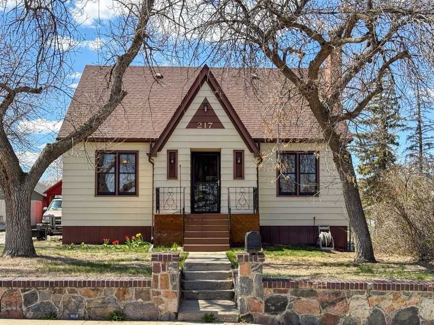 You’ll love this classic, tudor-style home, featuring charming details from the past, including built-ins, archways, and real hardwood floors, while also incorporating tasteful updates such as a tiled shower and double-sink vanity. The living room invites you to relax by the wood-burning fireplace and flows into a formal dining room, which leads to a kitchen with an additional eating space and an abundance of storage and cabinetry. Also, on the main floor, are two bedrooms and a full bathroom with shower/tub. The lower level offers a recreation room, another full egress bedroom, with newer laminate flooring, a flex room, spacious laundry area, and a beautifully-remodeled bathroom. On the way up to the second level, you’ll appreciate the inviting wooden staircase with a landing at the top and find an over-sized primary bedroom with a walk-in closet, along with an additional bedroom. The property is partly fenced and features mature landscaping with large shade trees, attractive shrubs and a real stone wall with steps that take you to the original real-wood front door. Out back, there is plenty of space to sit and barbecue on your Trex deck. A detached two-car garage—recently painted—provides plenty of additional space. Shelby is a small rural town with full services and with close proximity to hunting, fishing, recreation and a short drive to Canada and Glacier National Park. House should go VA, FHA and RD.