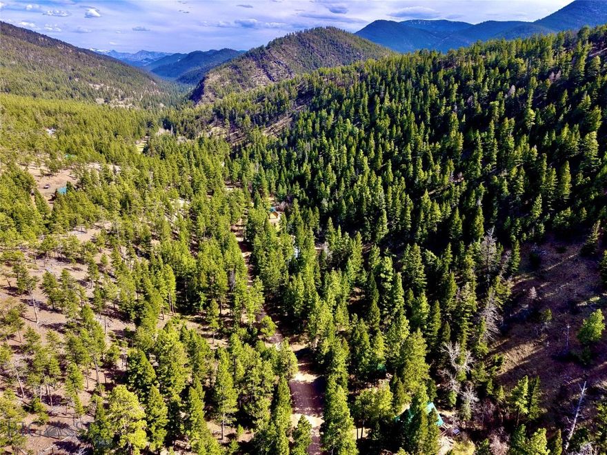 Tucked into the Helena National Forest, this classic Montana log cabin radiates on 11.5 acres. As you pull in off the gravel road, the first thing you notice is the quiet, the sound of wind moving through the treetops, the soft rush of Little Wolf Creek, and the distant call of birds echoing through the canyon. Built for comfort after long days outdoors, the cabin offers 2 bedrooms, 1 bathroom, and a loft space, with the kind of warm, rustic character that only a real log home can deliver. Inside, you’ll find a cozy layout designed for making memories — from hunting weekends with friends to quiet winter nights when the woodstove is glowing and snow is falling outside. And best of all: much of the furniture and personal property is included, so you can start enjoying it immediately. Down by the water, a lounge swing near Little Wolf Creek becomes your front-row seat to everything the forest offers. In summer, you’ll hear the creek sliding over smooth stones. In fall, you’ll smell crisp leaves and woodsmoke in the air. In spring, you’ll watch the landscape come alive again — bright green, loud, and fresh.
A major bonus for recreation buyers: this property is set up for the way Montanans actually live.
• Detached oversized insulated 2-car garage (32’ x 28’)
• Quonset (30’ x 24’) with concrete floor
• Plenty of space for ATVs, drift boats, snowmachines, trailers, tools, and hunting gear
Whether you’re here for hunting season, fishing season, or just to escape into the woods, this location puts you in the middle of it all:
• Hiking and camping throughout the surrounding forest
• World-class fishing on the Missouri River corridor
• Holter Lake boating, swimming, and camping nearby
• Hauser Lake and Canyon Ferry for more fishing, water sports, and recreation
• Endless opportunities for exploring public land, wildlife viewing, and backroad adventures
Hunters will appreciate the cabin’s proximity to millions of acres of public land and the region’s reputation for big game and upland bird hunting. Anglers will love being close to some of Montana’s most legendary waters — where early mornings mean tight lines and cold hands, and afternoons mean stories that get better every time they’re told. This is the kind of property that becomes part of your family story. The place where kids catch their first fish. Where friends come for opening weekend. Where the firepit always has one more chair pulled up, and the creek always sounds the same.