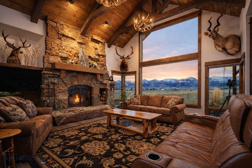 Discover the essence of Montana living on this remarkable 40-acre estate. Located within a gated community with an additional private, paved entrance through Spain Bridge Meadows, the property offers unmatched privacy surrounded by natural beauty. Residents enjoy community access to the Gallatin River along with walk and ride easements for effortless outdoor recreation. Inside, natural light fills the home through expansive windows that frame the mountains from nearly every angle. Beautiful timberwork runs throughout the main living areas, and a dramatic wood-burning fireplace anchors the great room. A beautifully appointed wet bar adds effortless convenience for hosting. The dining area opens fully to the covered patio through an accordion glass door, creating a seamless indoor–outdoor experience with an outdoor kitchen, wood-burning fireplace with gas starters, overhead heaters, a ceiling fan, and a hot tub, an ideal setting for year-round entertaining.The north wing includes an office, gym with rubber floor and the primary suite with expansive views, remote controlled blinds and a spa-like bath with a walk-through shower and tanning room. The south wing offers two bedrooms, a guest bath, pantry, laundry room, and access to the basement, garage, and attached guest apartment/suite- perfect for an au pair, multigenerational living, or long-term guests. A rare highlight is the fully equipped underground gun safe and 100 yard shooting range with vault door, pegboard gun holders, sound barrier, HVAC & ventilation system, retractable target system and camera system for target viewing, an extraordinary amenity that sets this property apart. With approval for up to three structures and room for four horses, the property offers exceptional flexibility. Just minutes from Bozeman, this estate blends luxury, privacy, and the wild beauty of Montana into a spectacular Montana sanctuary.