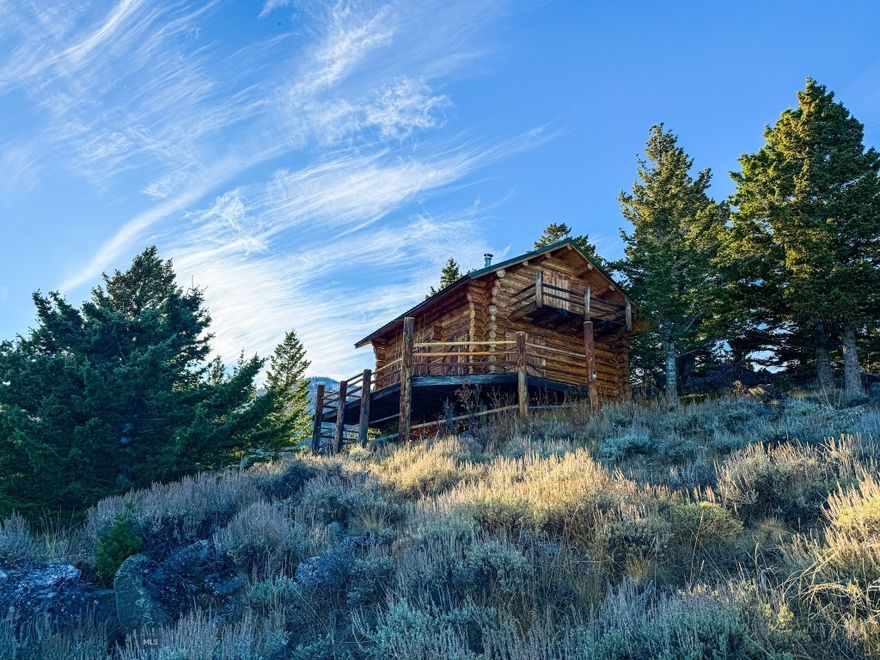 This 160-acre property offers a rare blend of natural beauty, solitude, and access to thousands of acres of public land. A year-round creek flows through the center, a feature of rare appeal at this elevation, winding between open meadows, mature timber, and dramatic rock formations. Set above the creek is a handcrafted, sun-drenched log cabin that takes in sweeping views of the surrounding ridges and valleys, offering a comfortable base from which to experience the property’s wilderness character. Expansive ridge lines offer panoramic views of multiple surrounding mountain ranges, with a sense of remoteness that’s increasingly hard to find. Occupied structures above or at the same level as this cabin are few and far between.

Insurable access is provided from the east, entering the lower end of the property via a road extending north from Charcoal Creek. Additional access reaches the upper portion and cabin site from Pony Creek Road, crossing Bureau of Land Management (BLM) land before entering the property. The main easement road could be improved or potentially rerouted to suit a future owner’s plans, offering flexibility without compromising the property’s secluded nature.

The cabin, built more than 30 years ago from hand-peeled Bitterroot lodgepole pine, reflects craftsmanship and character rarely found today. Constructed by the property’s longtime owner—one of the first recreational buyers in the area—it includes custom cabinetry, a composting toilet, an efficient wood stove, skylights and a sleeping loft. The cabin is comfortable year-round, sleeps up to five, and can convey furnished with most contents, excluding personal artwork, Navajo rugs, and antique skis.

This region supports a healthy population of wildlife, with the property serving as a natural corridor for elk, mule deer, black bear, and other native species. The variety of habitat—from grassy benches and shaded creek bottoms to forested ridges—provides reliable year-round movement and excellent opportunities for observation or hunting.

Beyond its recreational and wildlife value, this property combines practical accessibility with true wilderness solitude. Despite its quiet, off-grid character, it lies just over an hour from Bozeman, placing essential amenities, airports, and year-round services within easy reach. Properties offering this degree of privacy, live water, and direct public-land adjacency are becoming increasingly rare in southwest Montana.