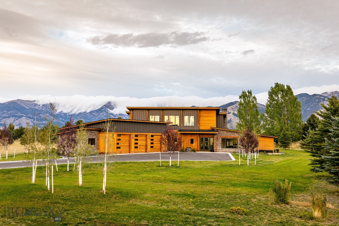 Discover a true architectural masterpiece in this stunning home in exclusive Bridger Lake Meadows. Situated on a lushly landscaped acre, the homesite backs to open space to protect the breathtaking Bridger Mountain views. Upon entering this fine home, one is taken by the exceptional finishes at every turn, like custom solid walnut interior doors and a carefully curated lighting package. The panoramic breathtaking views from every window and outdoor space effortlessly blend architectural brilliance with luxurious livability. Ideal for both private relaxation and elegant entertaining, this home showcases floor-to-ceiling windows that seamlessly connect interior spaces with the surrounding natural beauty. The great room makes a bold statement with the soaring ceilings, custom steel fireplace, floor to ceiling rock wall, wood ceiling and exposed steel beams, Hunter Douglas electronic shades and heated floors.
The primary suite is a private sanctuary, complete with a spa-like bathroom, spacious multi head shower, soaking tub, an expansive walk-in closet, and an adjacent owner’s living area with custom built-ins. Across the home, a private guest suite rivaling the finest hotel awaits the discerning guest. The beautifully appointed kitchen features professional Thermador appliances, built-in coffee/espresso maker, ice machine, LED lighting, and a butler pantry with cabinetry, custom shelving, sink, and freezer. The dining area has ample space for dinner gatherings and an adjacent bar with beverage/wine fridge.
The roomy upper level features another spacious bedroom with an adjacent luxe bathroom, a family room with beverage station, and a golf simulator.
Spanning over 4300 square feet of heated above grade square footage, the home offers additional storage with the partial basement, oversized three car heated garage with extra flex space attached. This exceptional property offers a rare combination of luxury, timeless elegance, design, and natural beauty, making it a true sanctuary for life's finest moments.