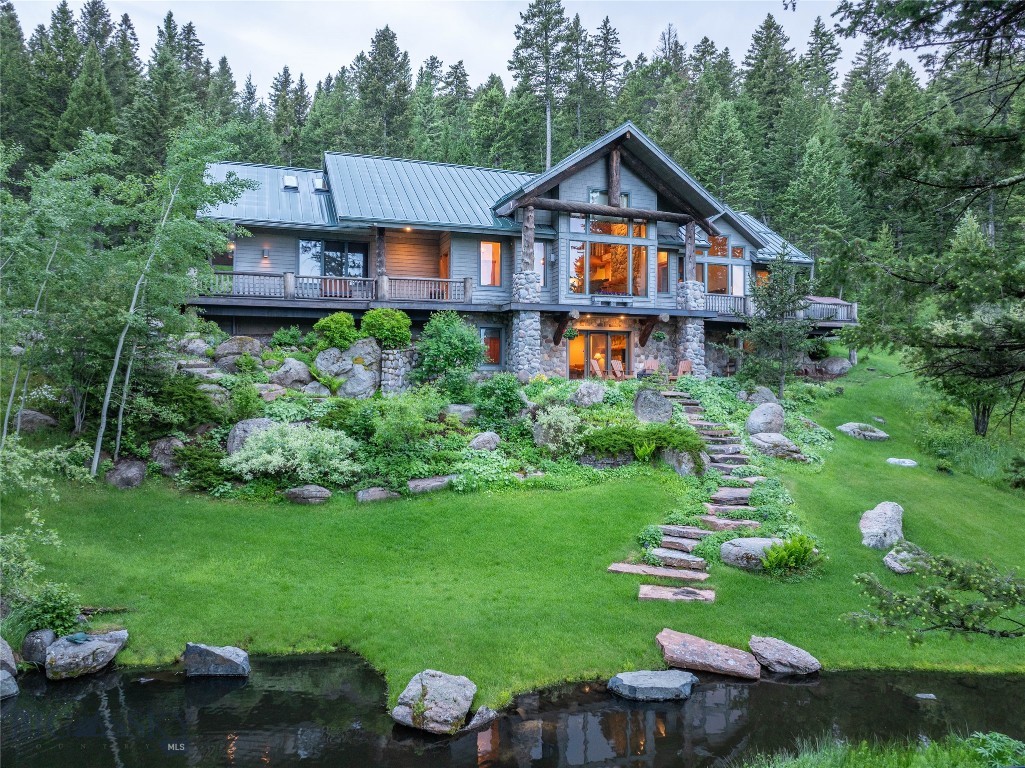 Welcome to 709 Limestone Road, a serene mountain retreat tucked into the forested hills of the exclusive Eagle Rock Reserve in Bozeman, Montana. Designed by renowned architect Faure Halvorsen and built by Jim Syth, this custom 4,516 SF home sits on 20 lush acres, offering a rare combination of privacy, tranquility, and proximity to town—just 15 minutes from downtown Bozeman. Set among mature trees, wildflowers, and professionally landscaped gardens, the property features two peaceful ponds with cascading water features, creating a park-like setting that invites relaxation and exploration. From the main living area, expansive windows frame stunning views of the Bridger Mountains, while the rest of the home is nestled in a canopy of evergreens, creating a true retreat atmosphere. Inside, thoughtful design and craftsmanship are evident throughout. The main level includes a spacious great room with vaulted ceilings, a floor-to-ceiling wood-burning stone fireplace, and rich wood accents that echo the natural surroundings. The open-concept layout flows seamlessly into the dining area and kitchen, making it ideal for gatherings. The main floor also features a private primary suite with serene garden views, offering easy single-level living. Downstairs, the walkout lower level includes a large family room with a second fireplace, three additional bedrooms, two full bathrooms, and direct access to a covered patio—perfect for guests or multigenerational living. The upper level offers a bright loft space and two office/studio rooms, ideal for creative work or remote professionals. Multiple outdoor living areas—including a wraparound deck, covered patio, and quiet sitting areas tucked into the trees—make the most of Montana’s long summer days and star-filled nights.
As part of Eagle Rock Reserve, residents enjoy access to a private equestrian facility, a stocked trout pond, community-maintained trails, and adjacent State Land for hiking, horseback riding, and outdoor adventures. With nearby access to Triple Tree Trail and National Forest lands, this home is a gateway to the Montana lifestyle—peaceful, private, and connected to nature, yet minutes from all that Bozeman has to offer.